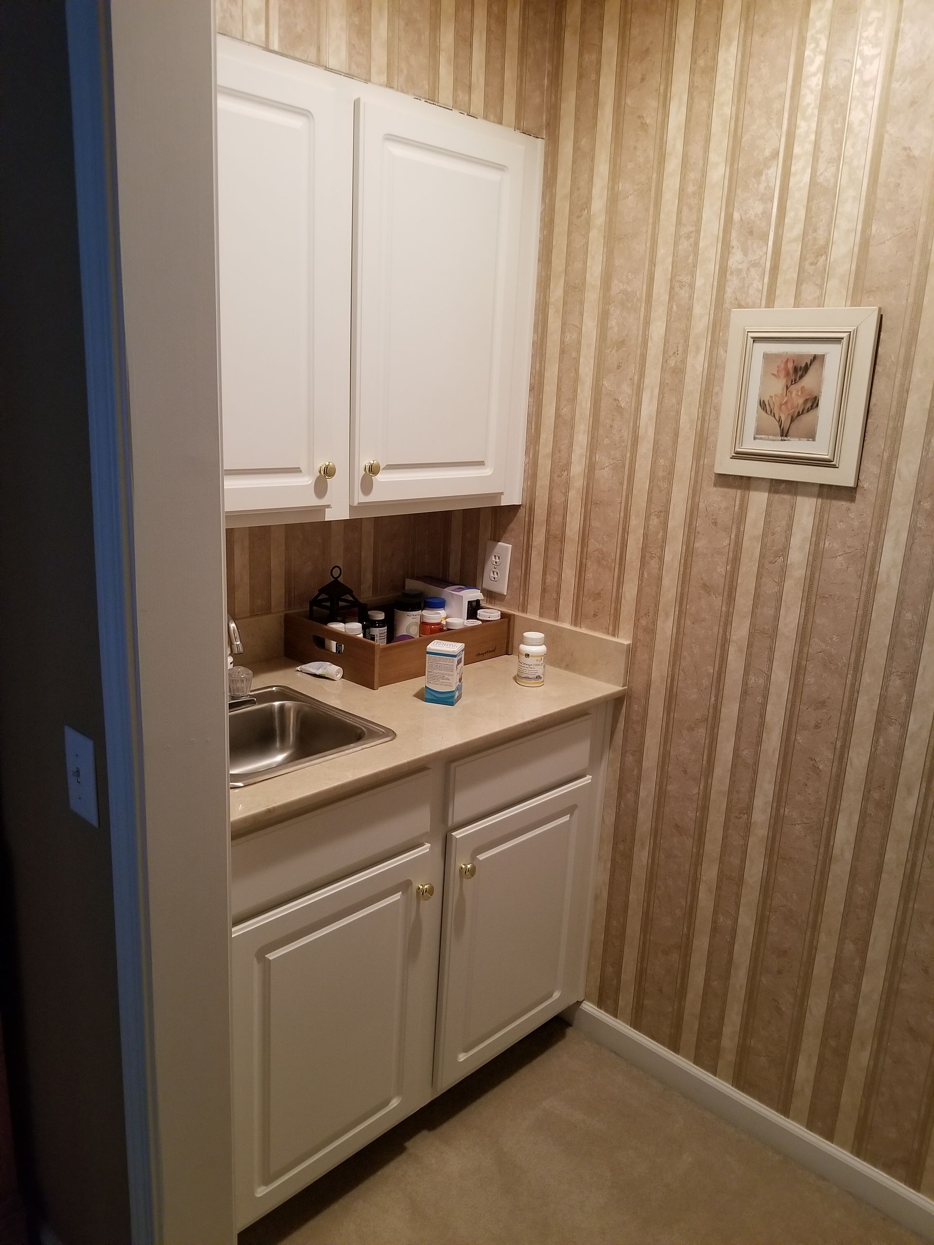 A small kitchen with white cabinets and a sink.