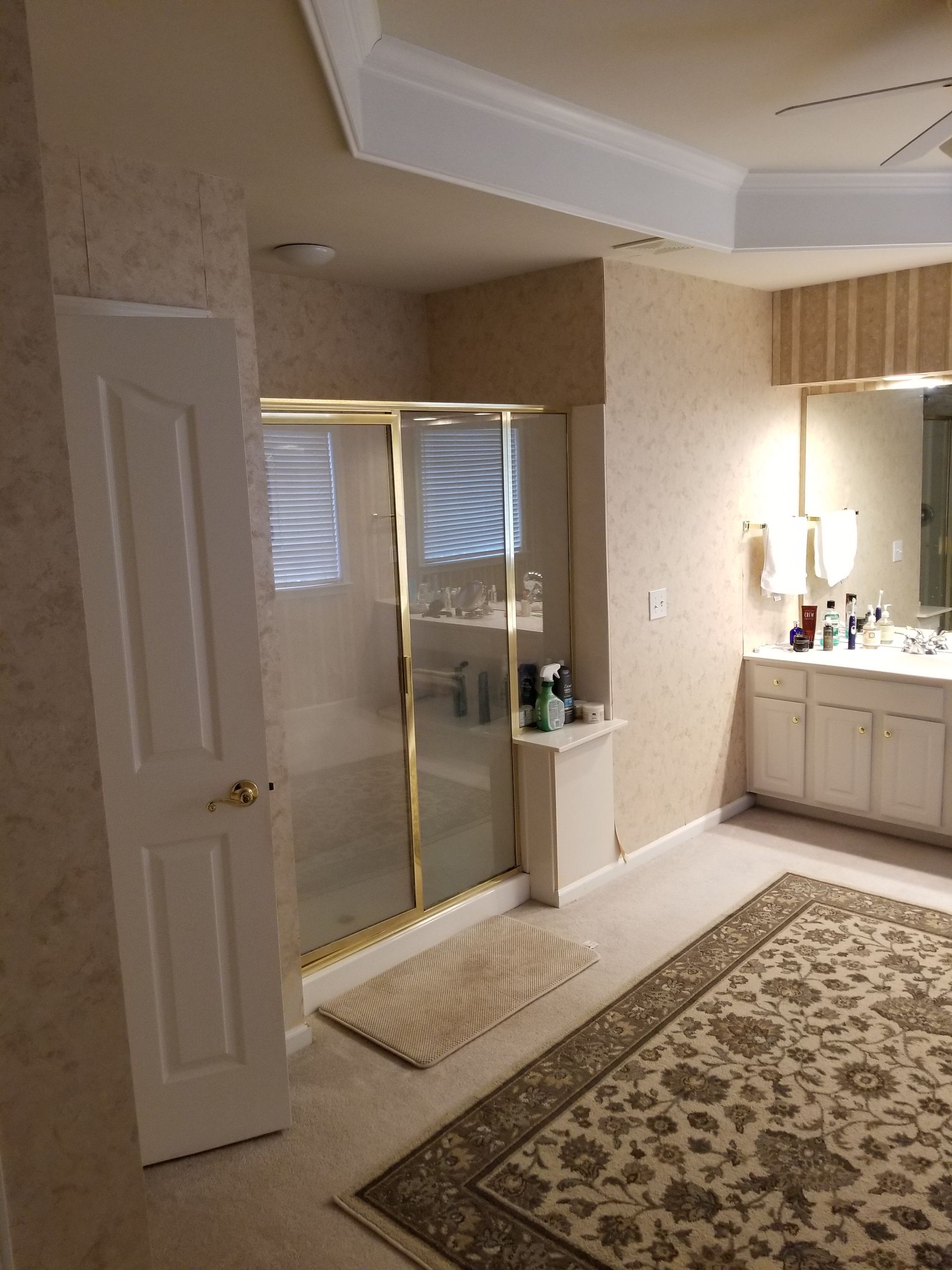 A bathroom with a walk in shower, sink, and rug.