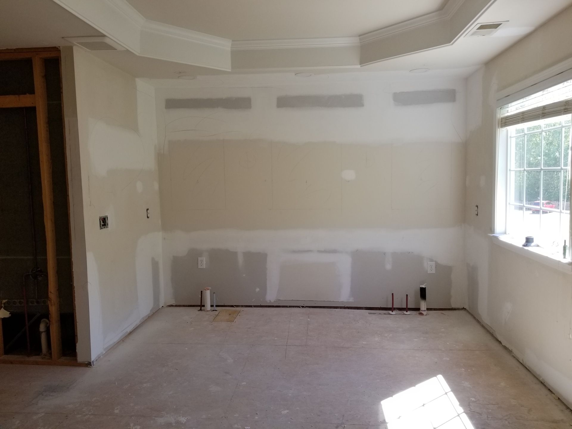 An empty room with a window and drywall on the walls