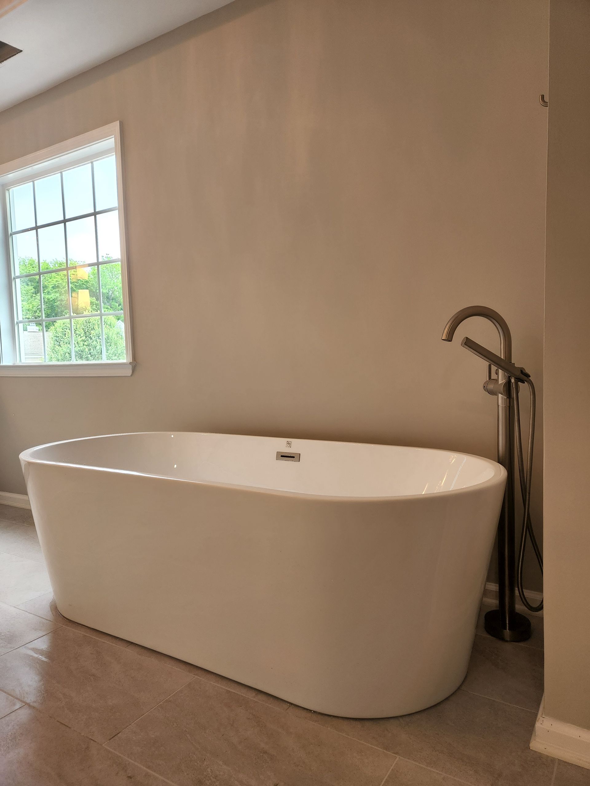 A white bathtub is sitting in a bathroom next to a window.