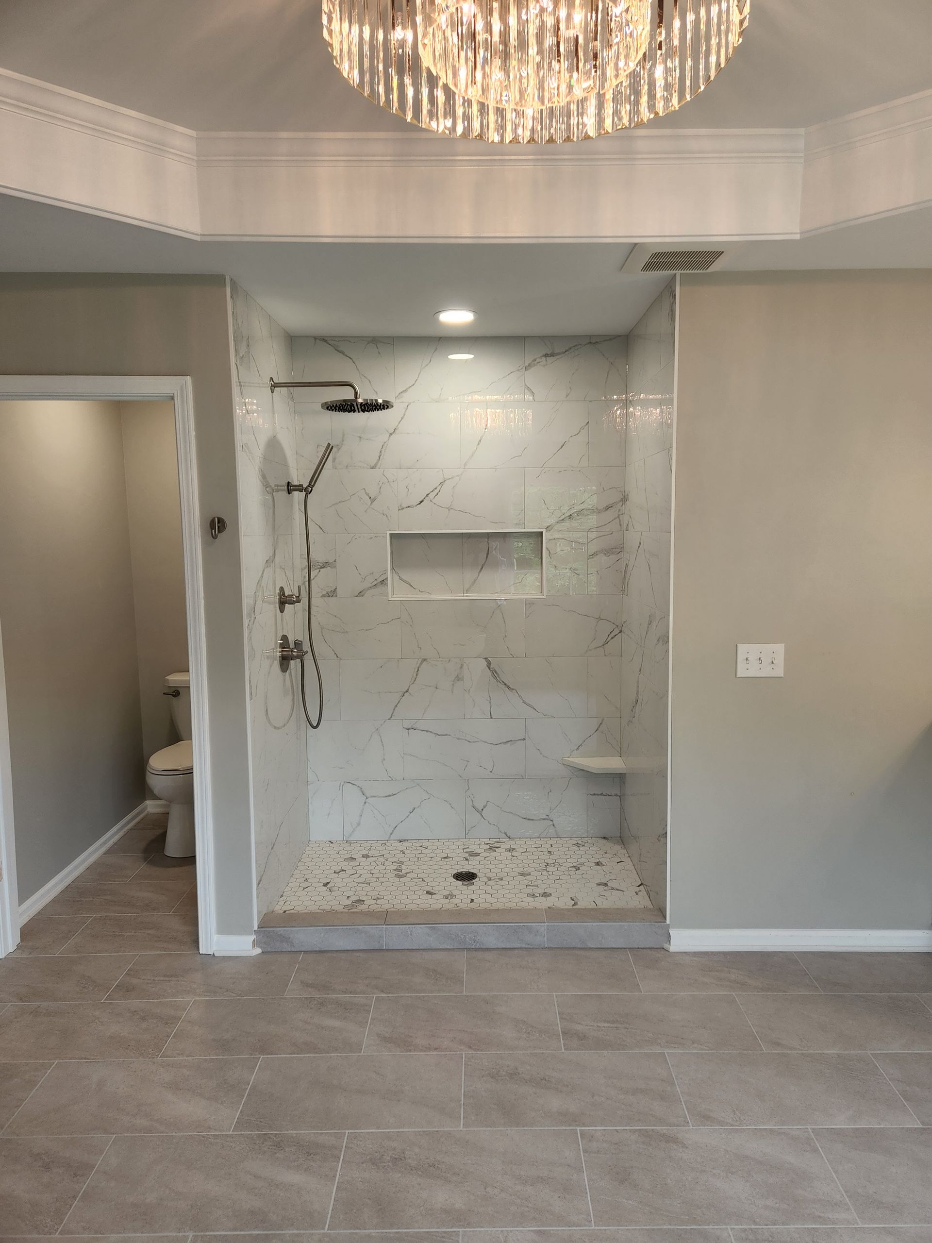 A bathroom with a walk in shower and a chandelier hanging from the ceiling.