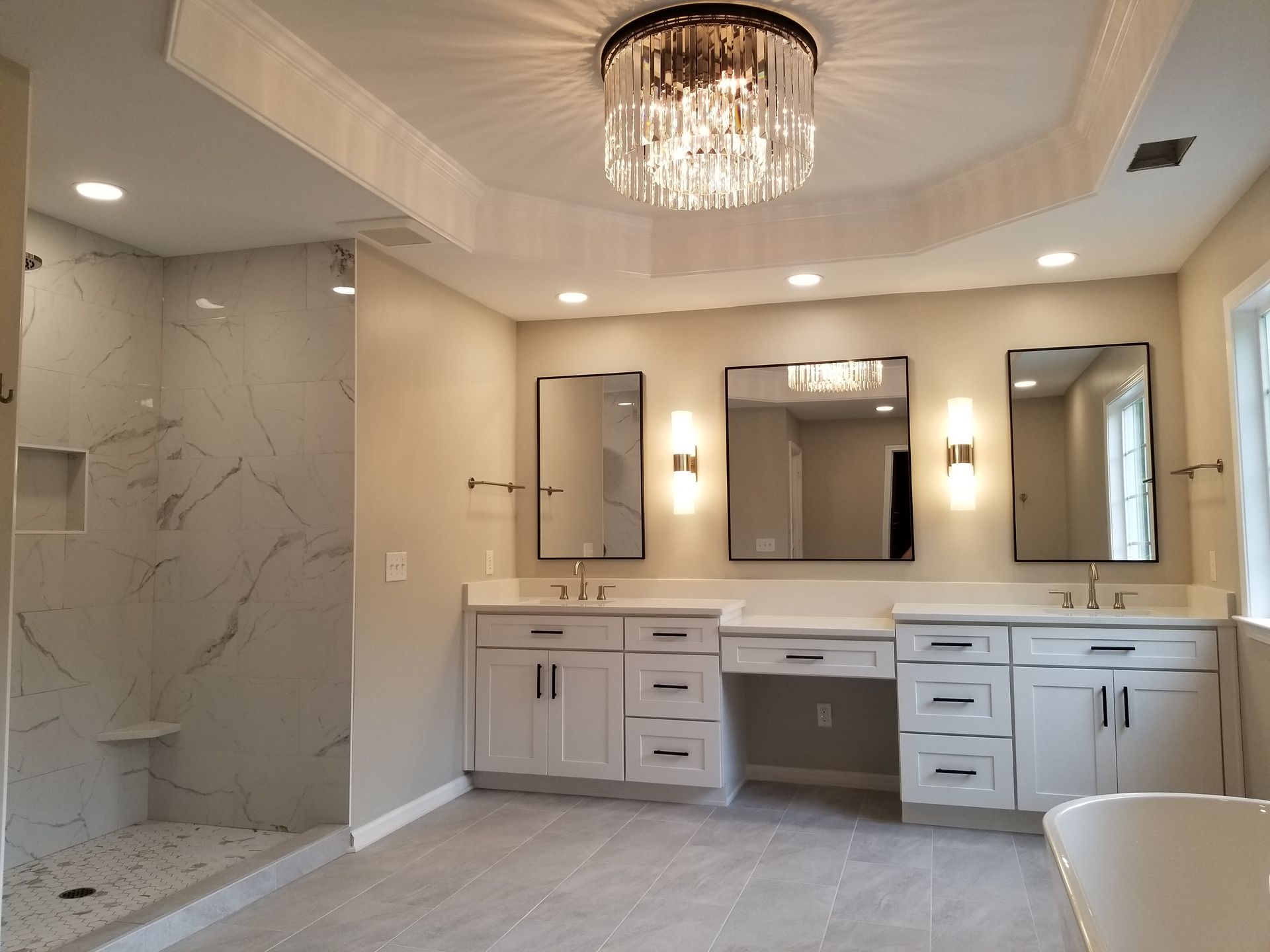A bathroom with two sinks , two mirrors and a chandelier.