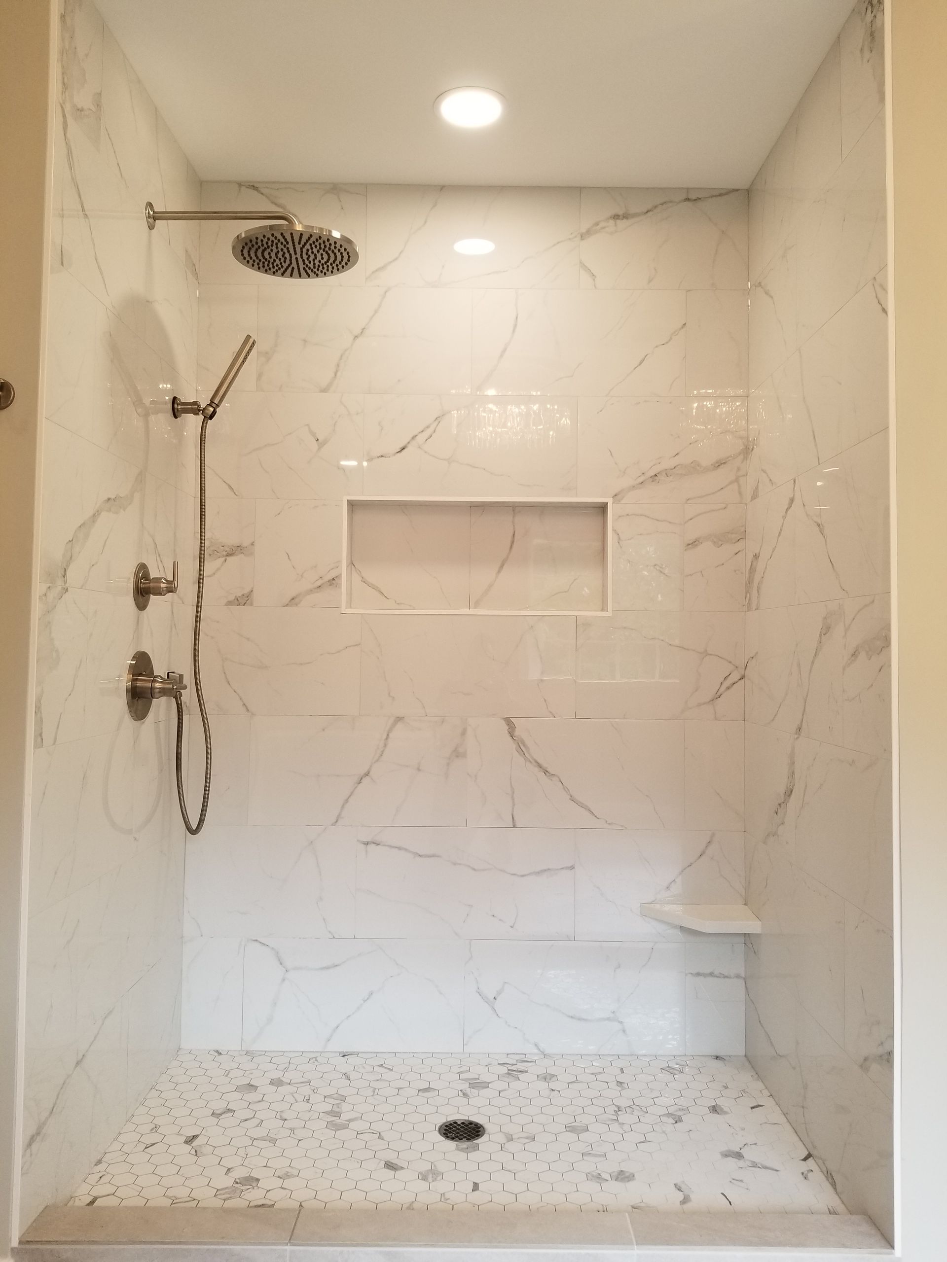 A shower with a shower head and a shelf in the wall.