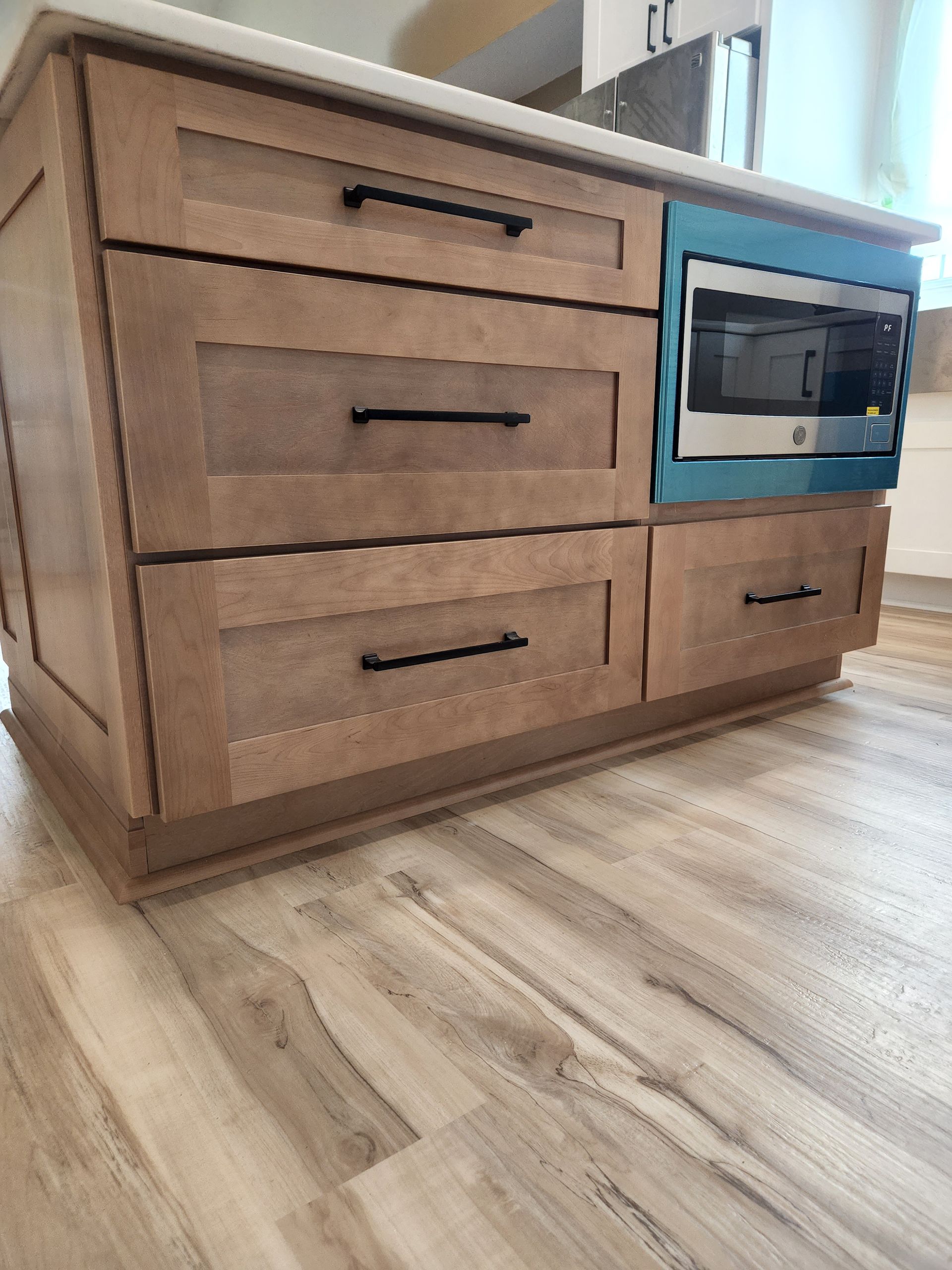 A kitchen island with drawers and a microwave on top of it.