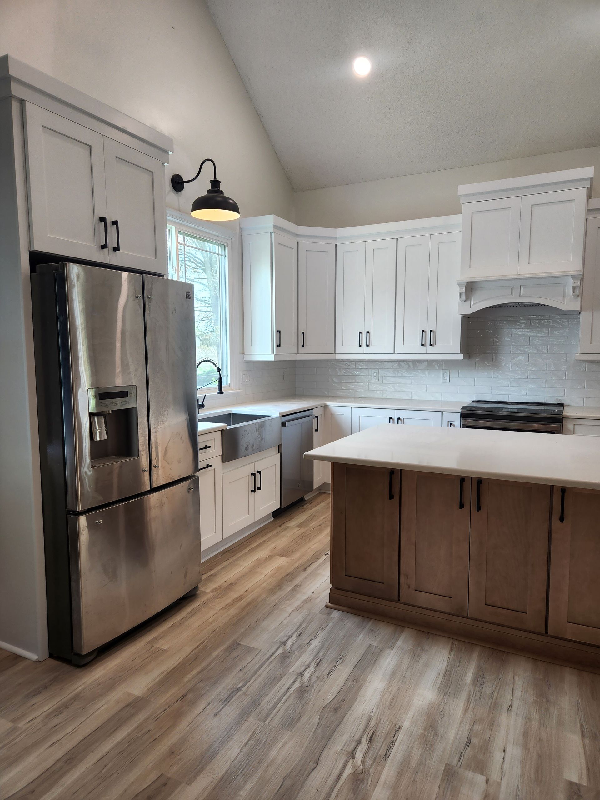 A kitchen with white cabinets , stainless steel appliances , and a large island.