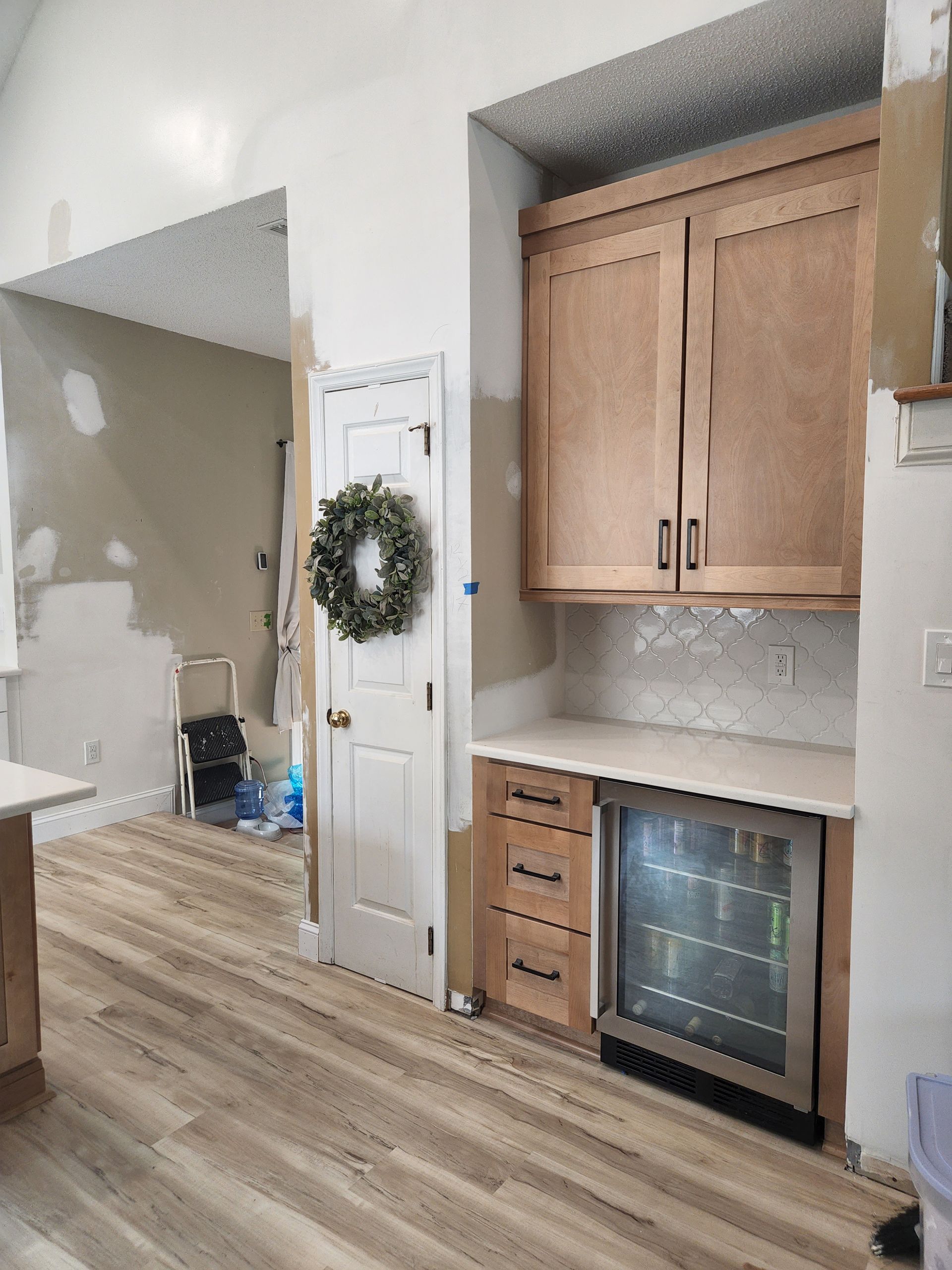A kitchen under construction with wooden cabinets and a refrigerator.