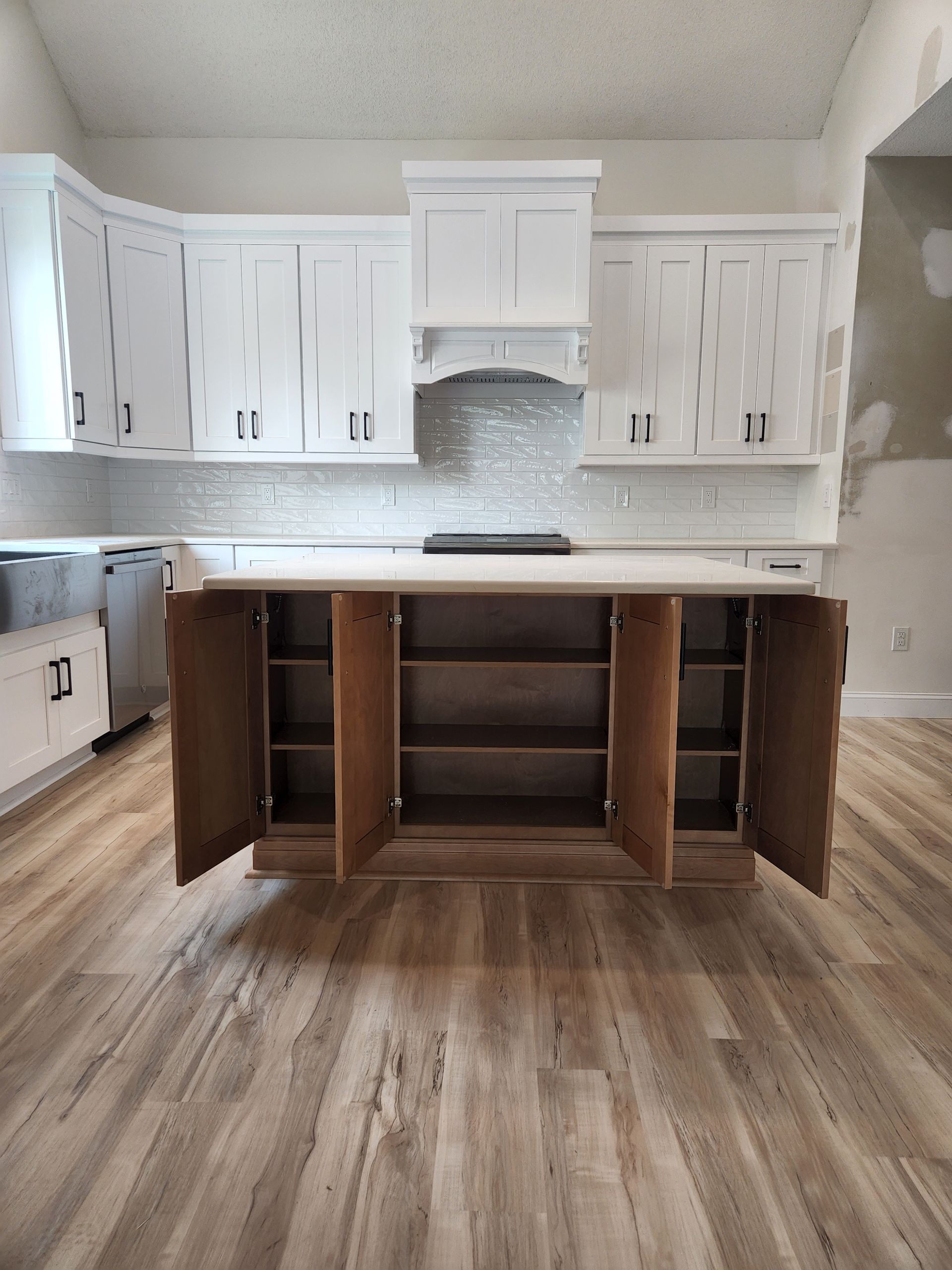 A kitchen with white cabinets and wooden floors.