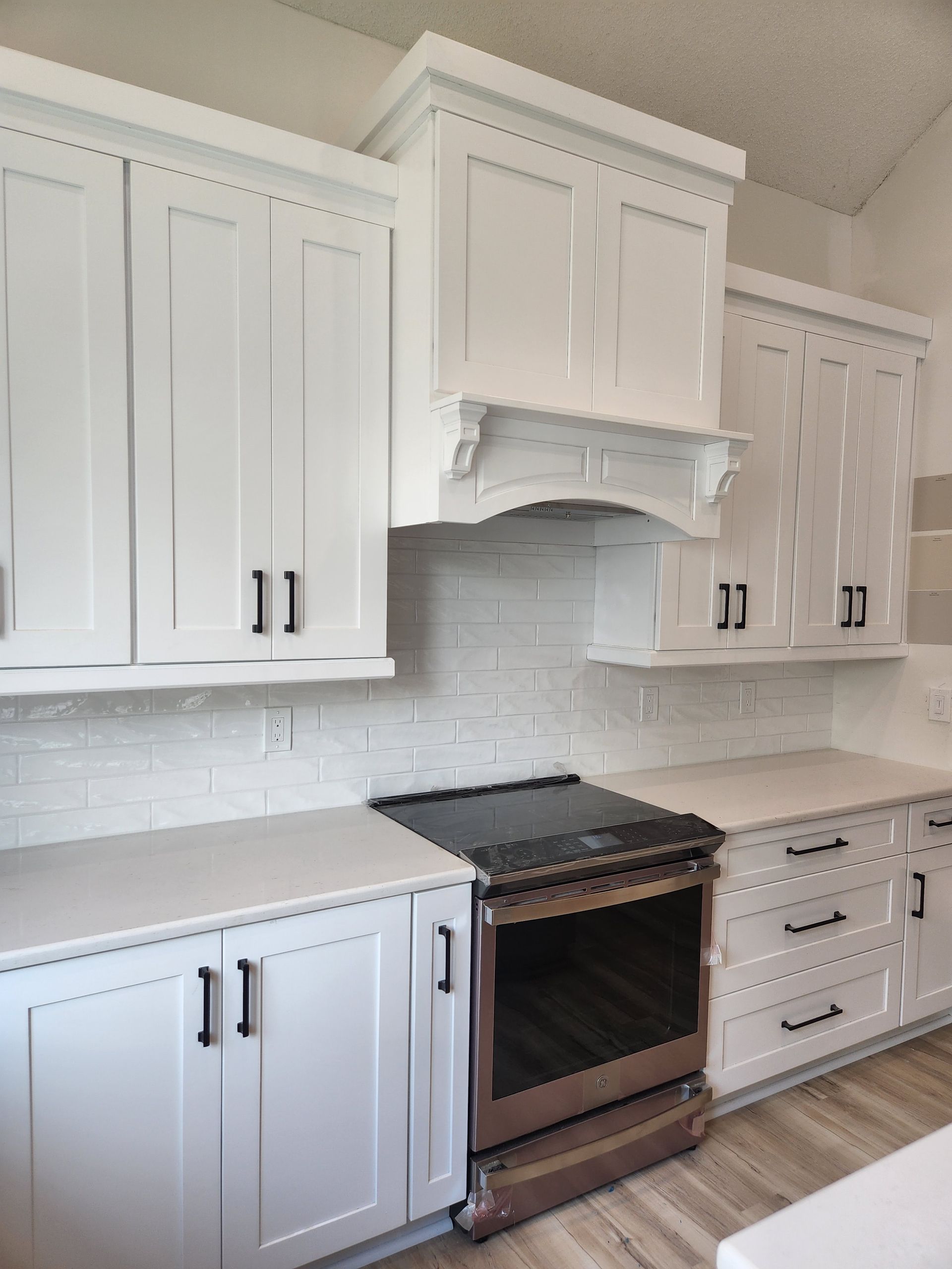 A kitchen with white cabinets and a stove top oven