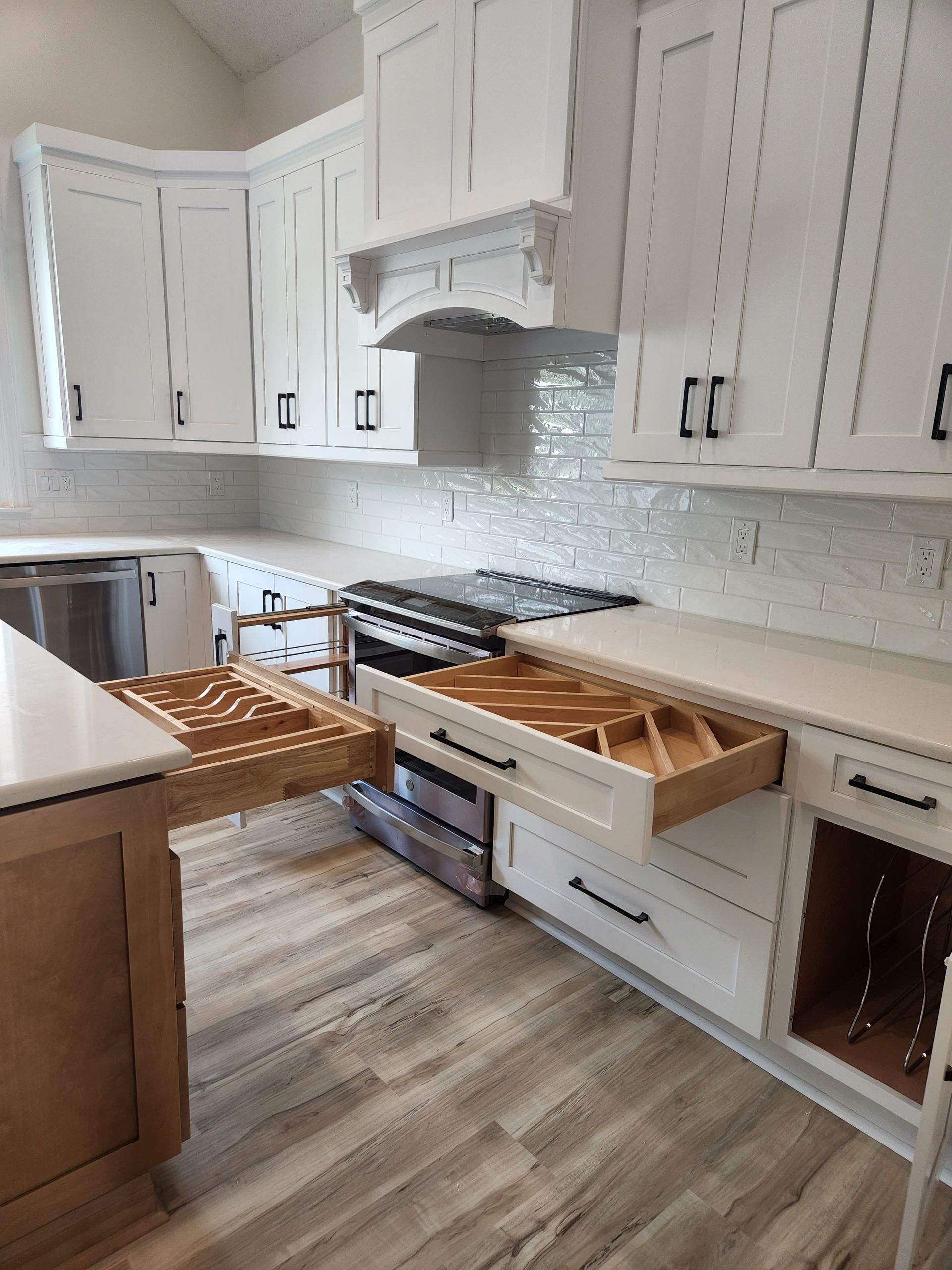 A kitchen with white cabinets and wooden drawers and a stove.