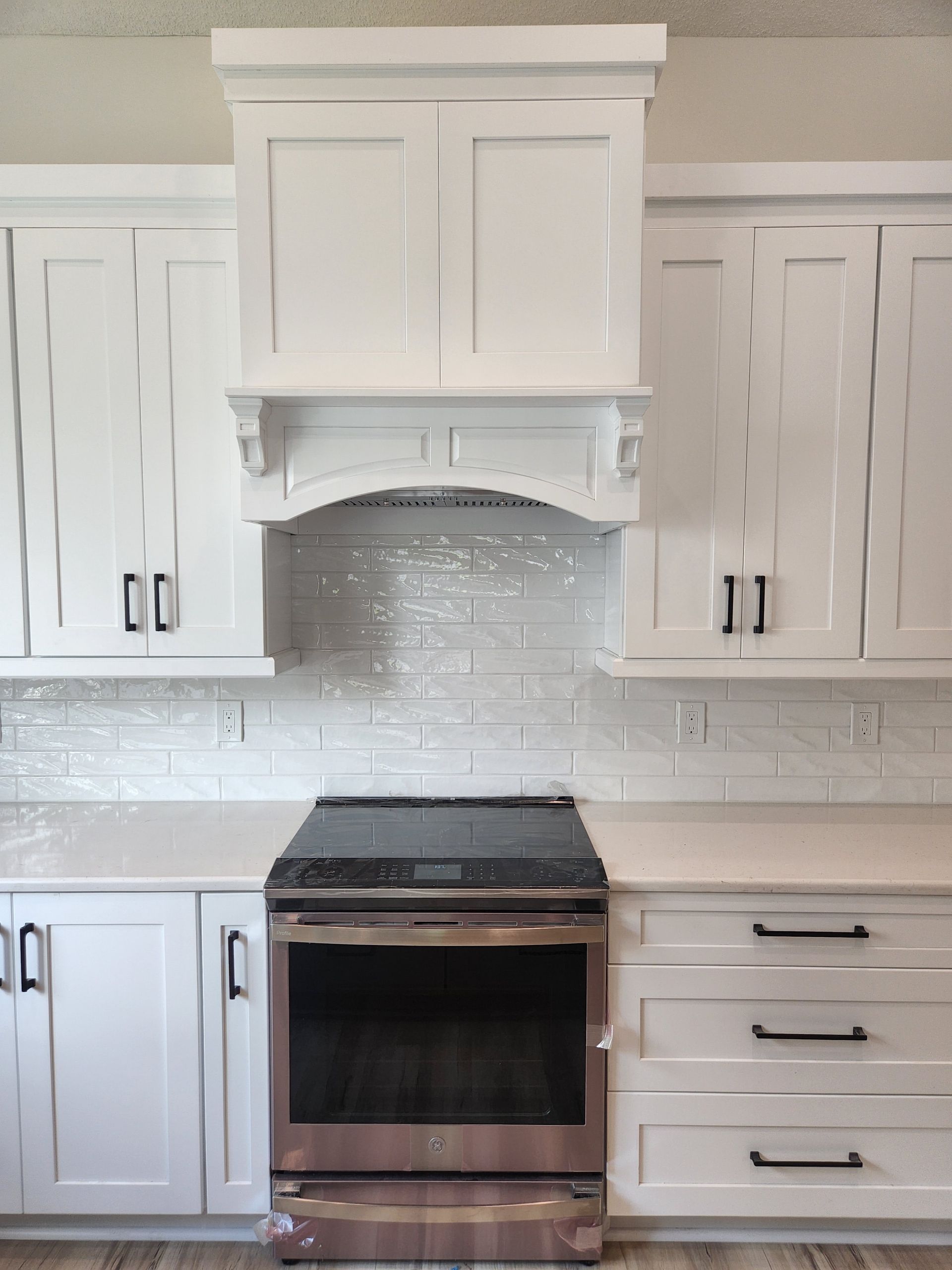 A kitchen with white cabinets and a stove top oven