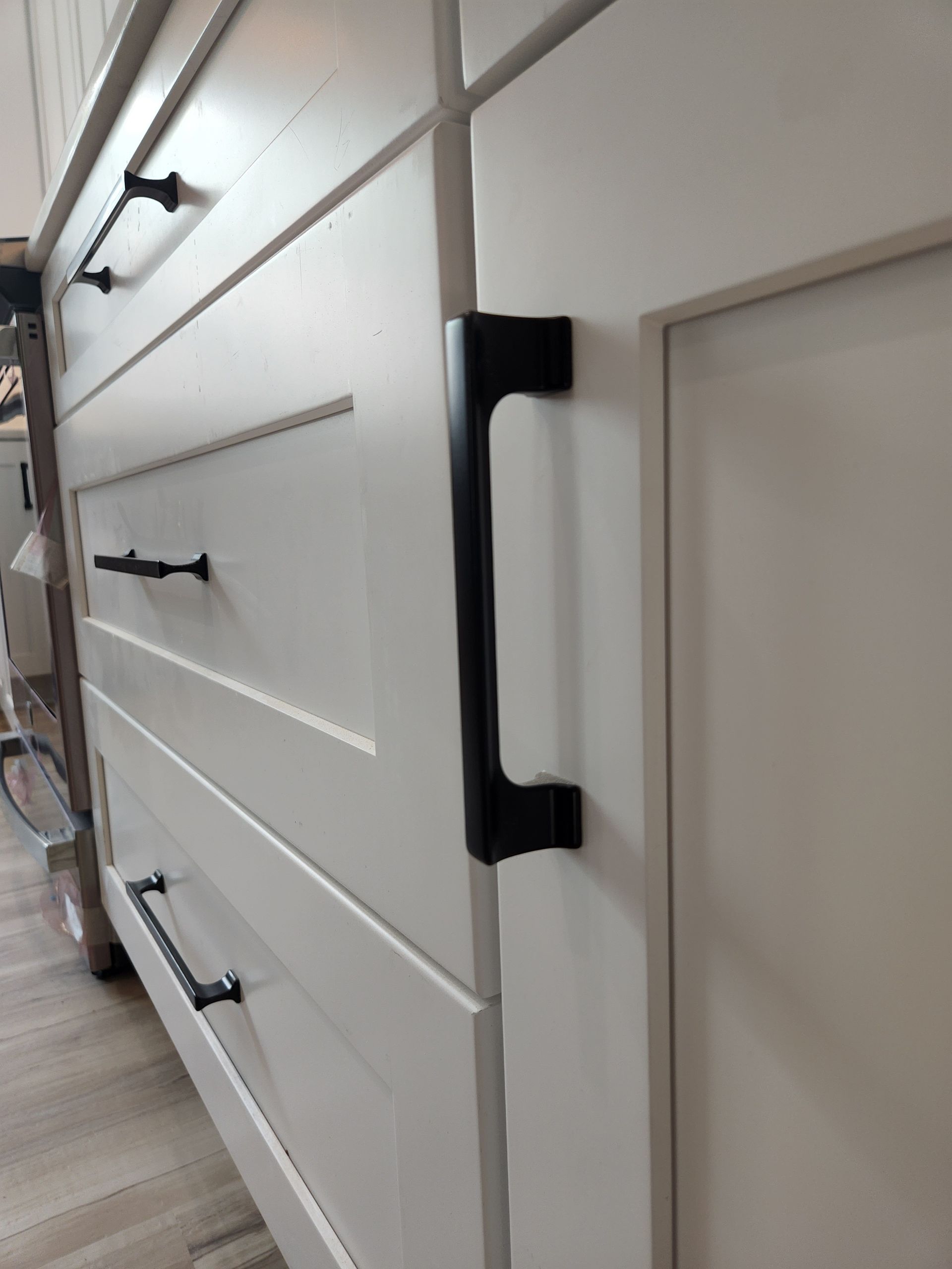 A close up of a kitchen cabinet with black handles.