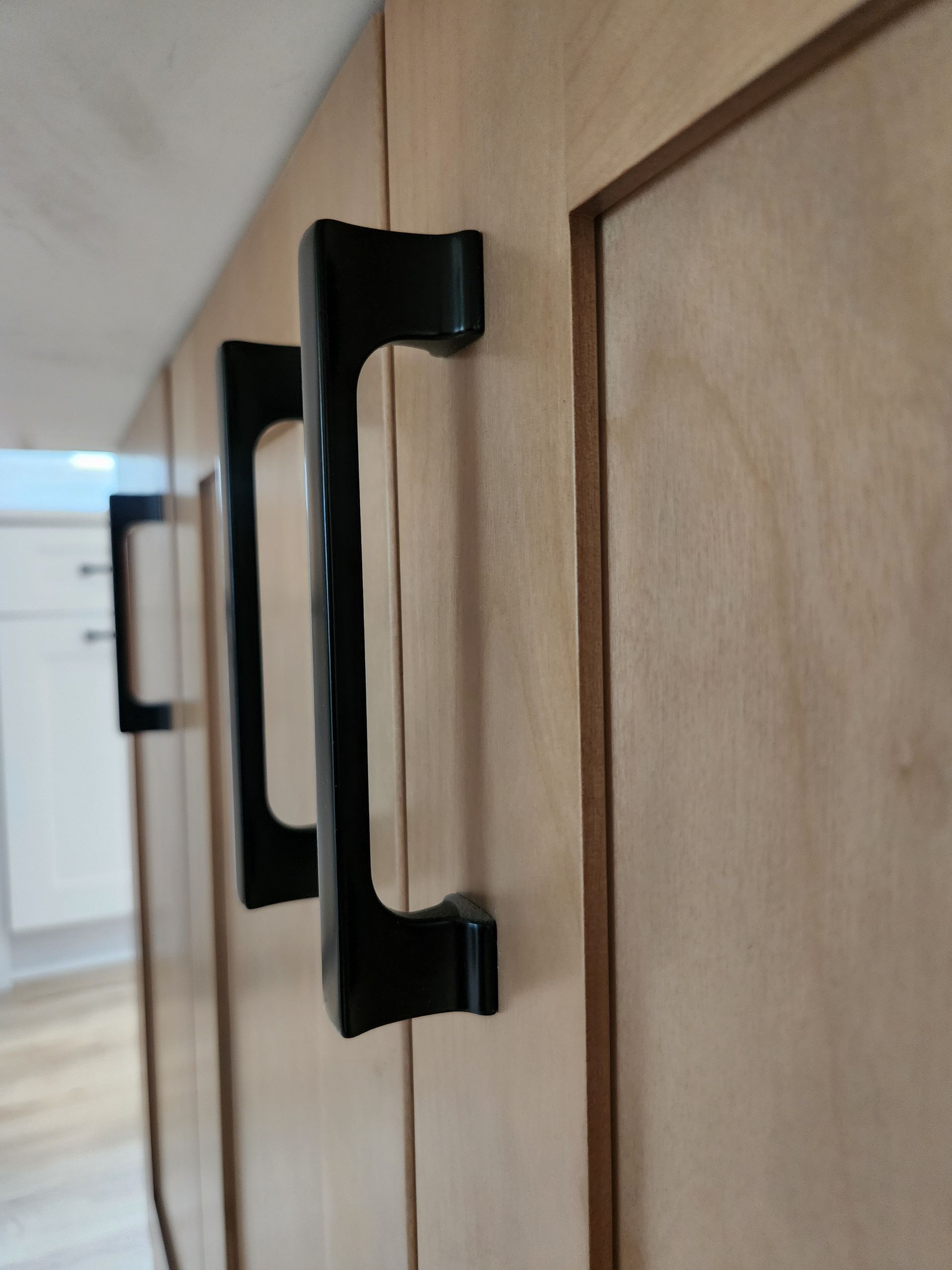 A pair of black handles on a wooden cabinet