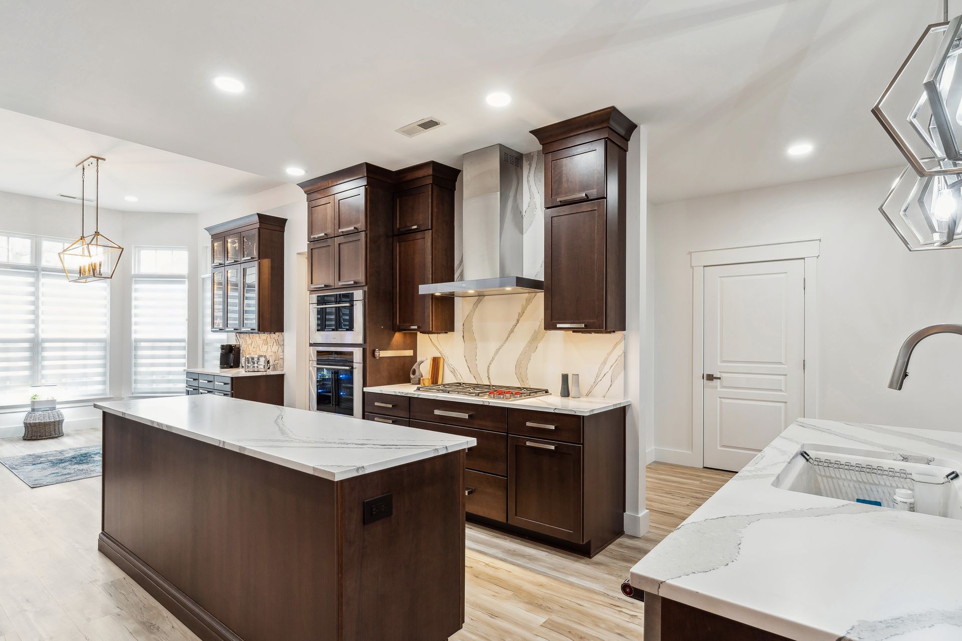 A kitchen with wooden cabinets, white counter tops, and a large island.