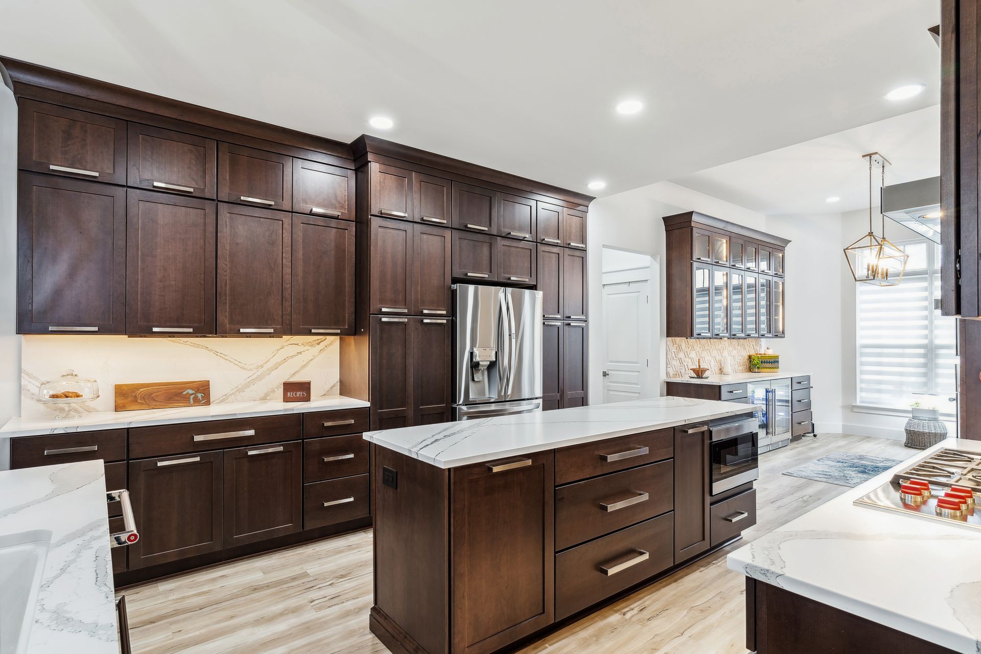 A kitchen with brown cabinets and white counter tops and a large island in the middle.