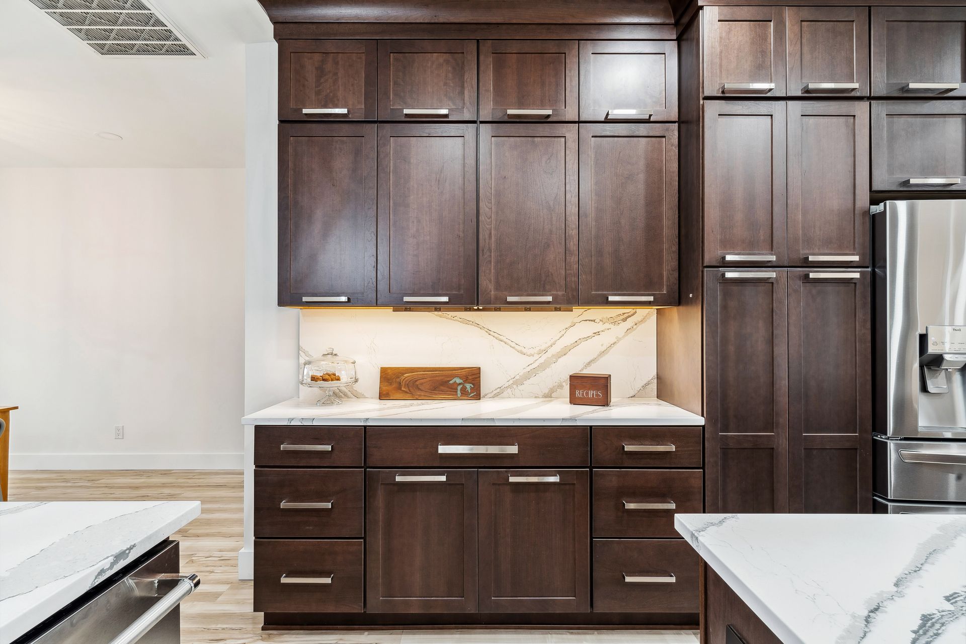 A kitchen with dark wood cabinets and white counter tops.