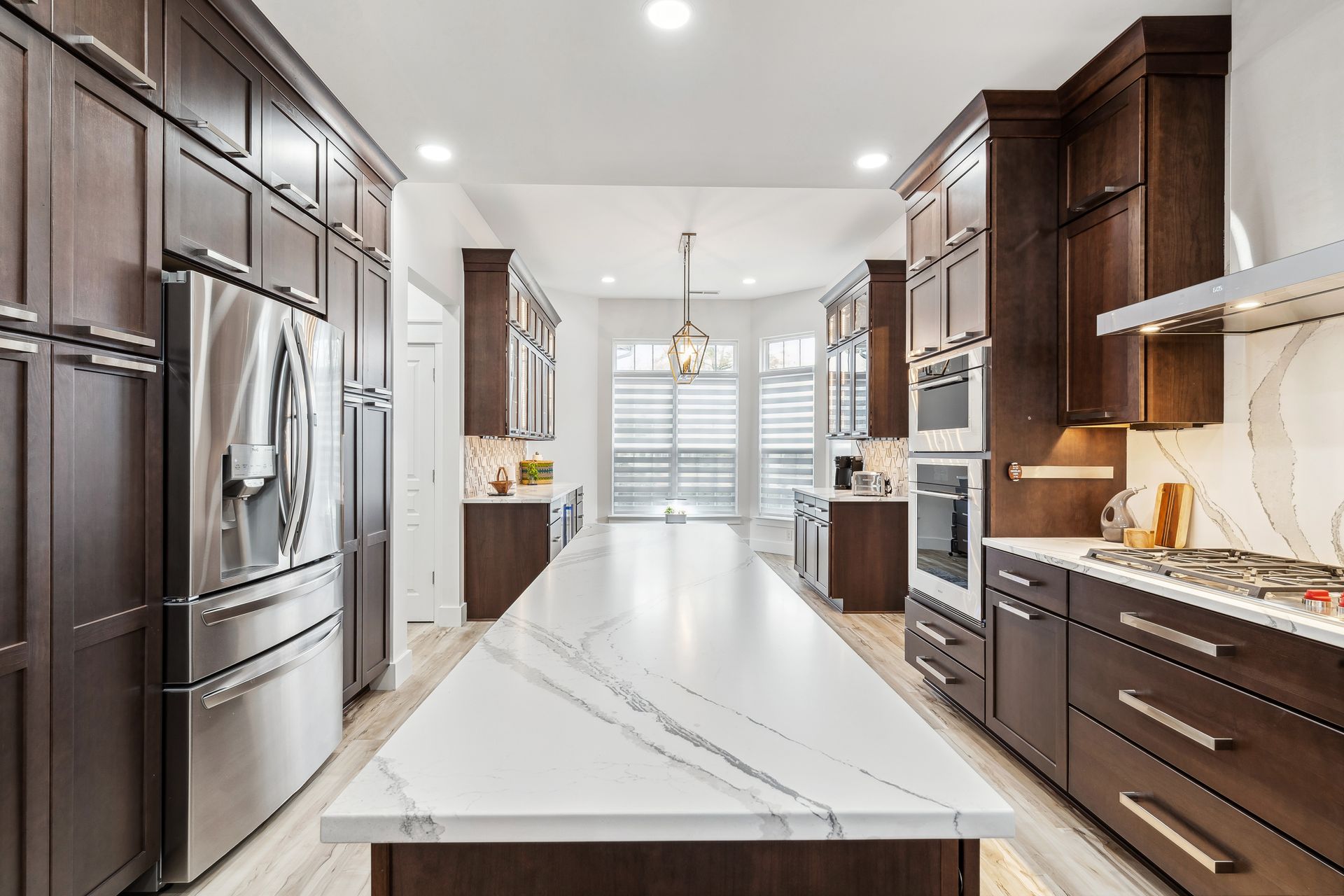 A kitchen with stainless steel appliances, wooden cabinets, and a large island.