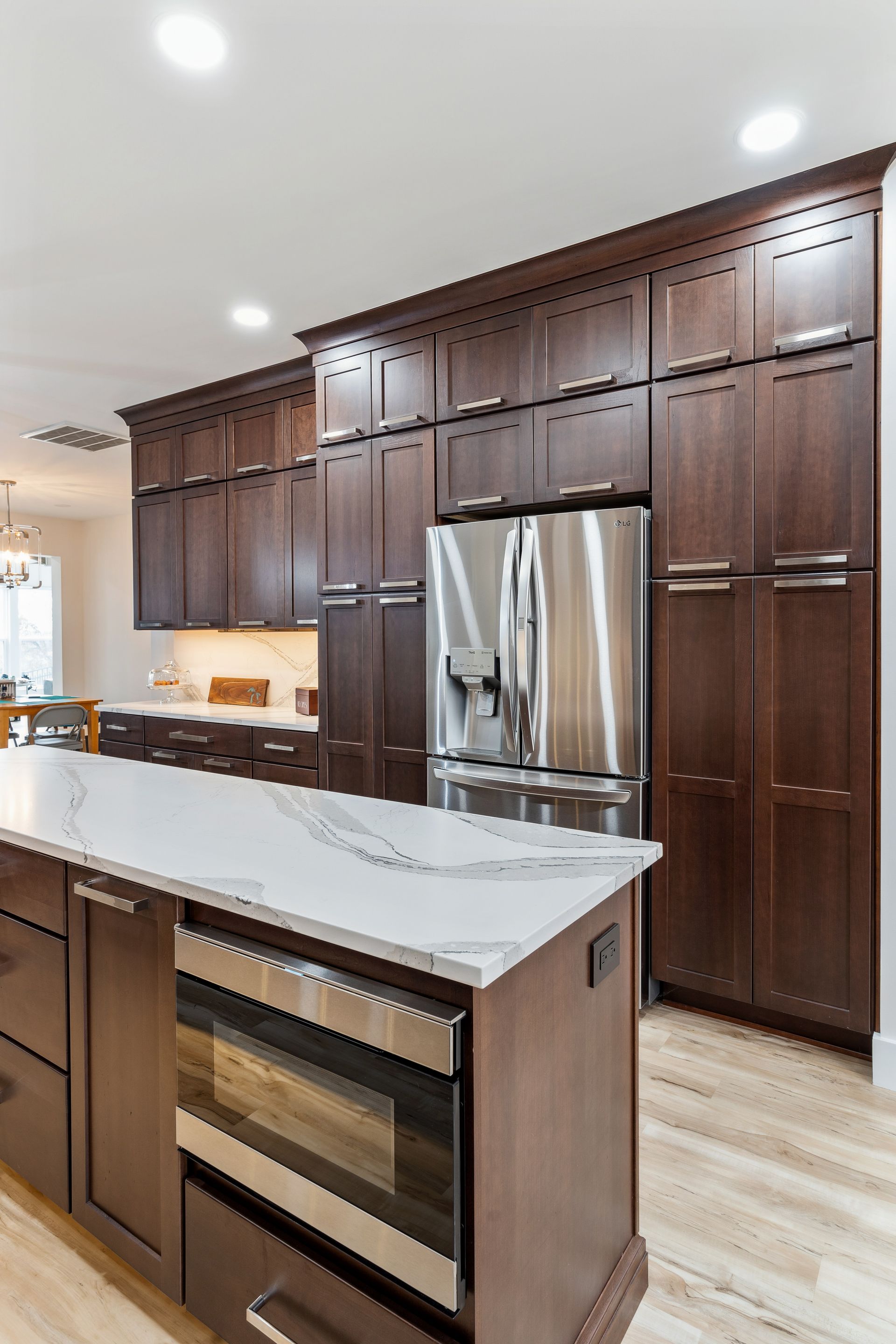 A kitchen with stainless steel appliances, wooden cabinets, and a large island.