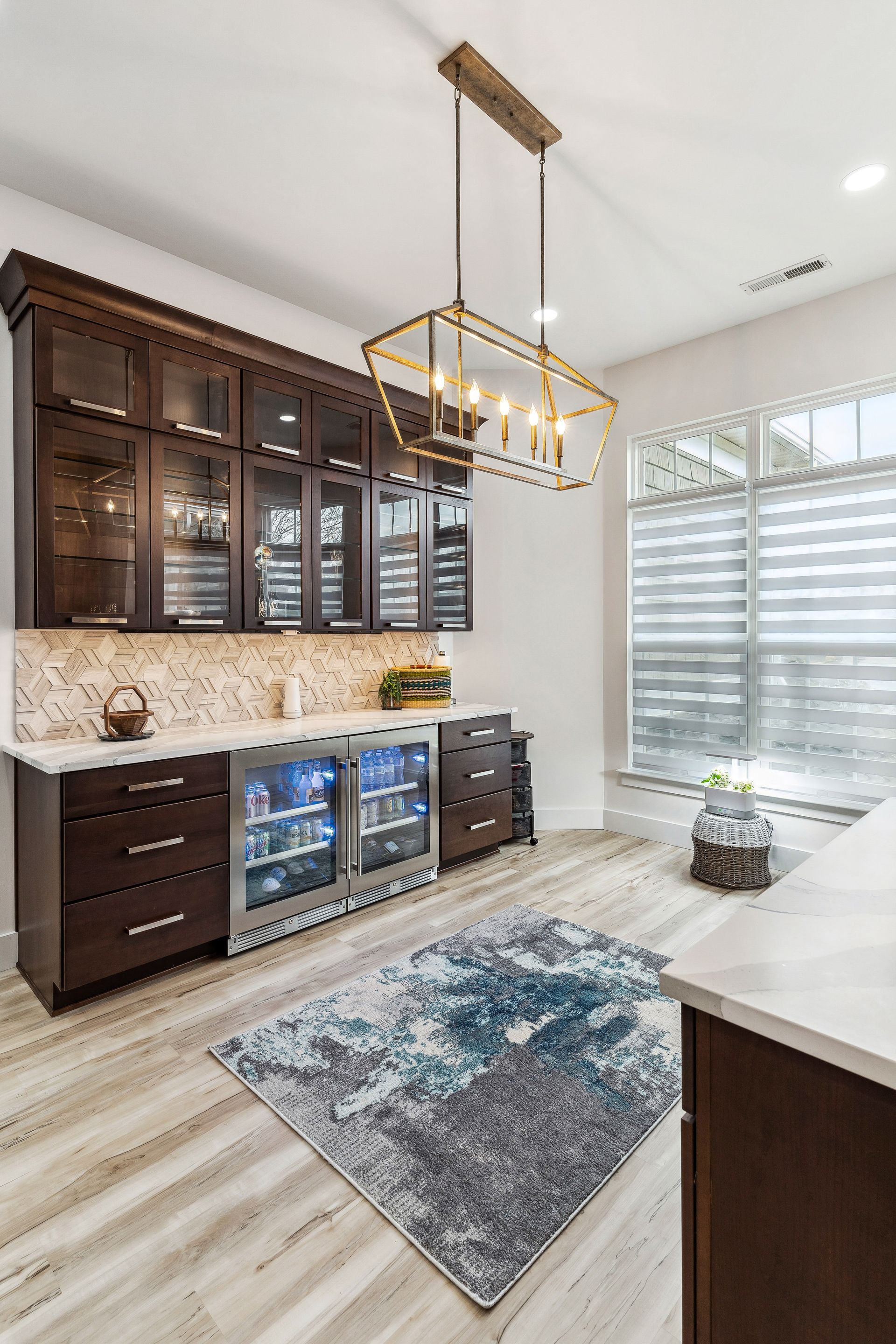 A kitchen with stainless steel appliances, wooden cabinets, a rug and a chandelier.