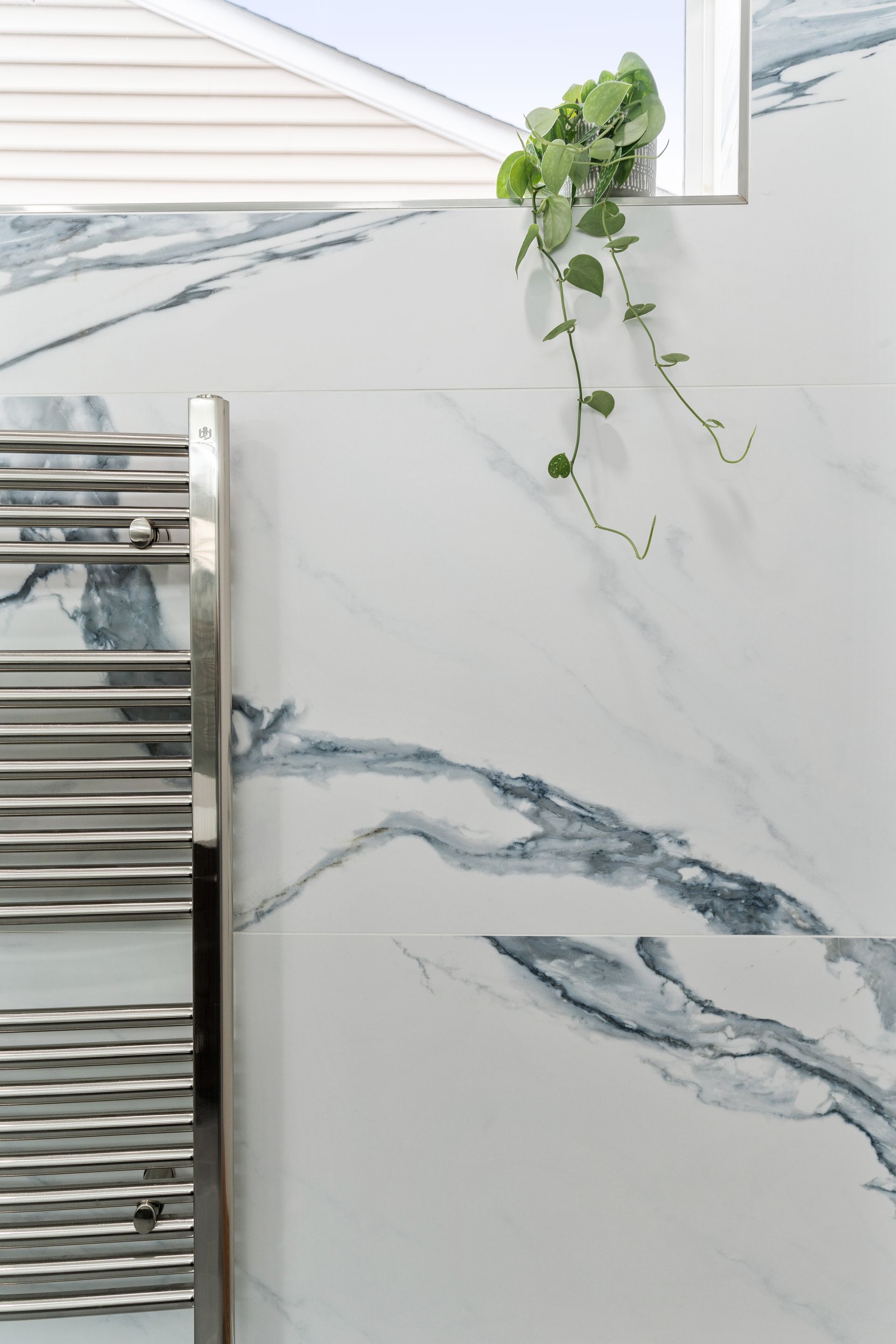 A bathroom with a towel rack and a plant on the wall.