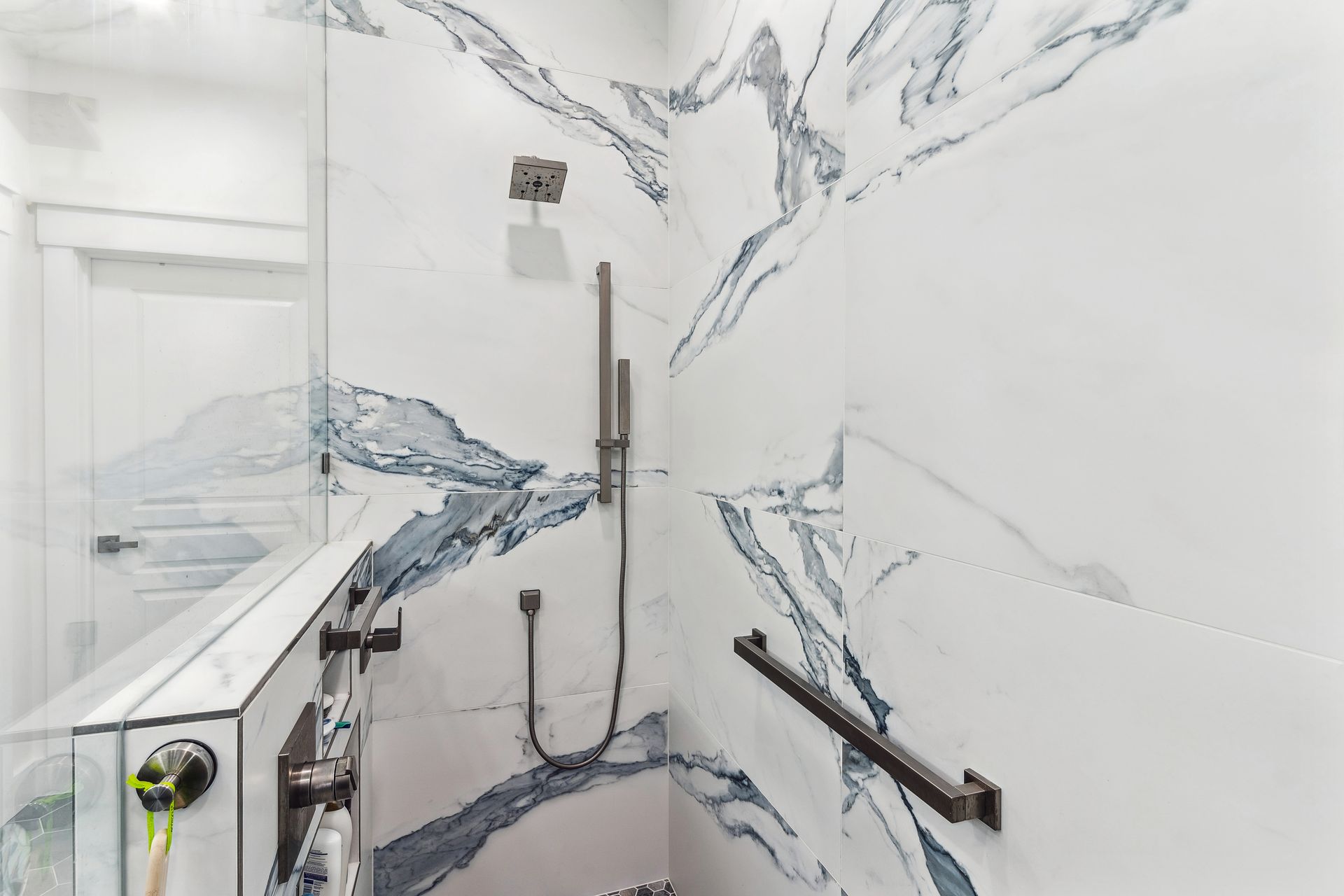 A bathroom with a walk in shower and a marble wall.
