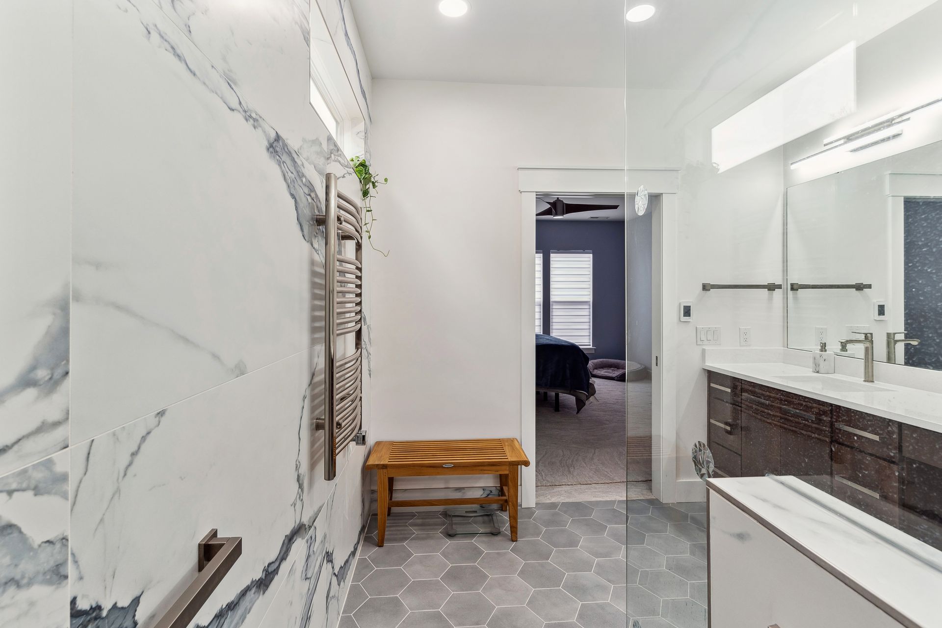 A bathroom with a walk in shower and a bench.