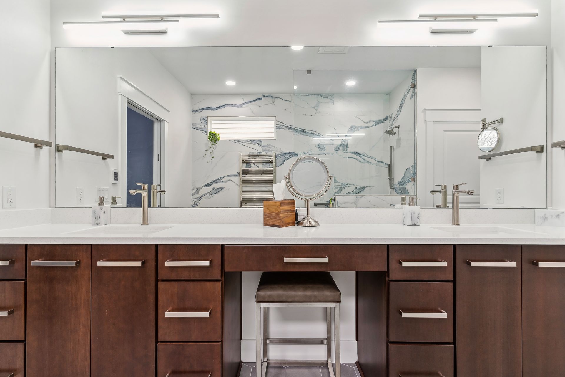 A bathroom with two sinks , a vanity , a mirror and a stool.