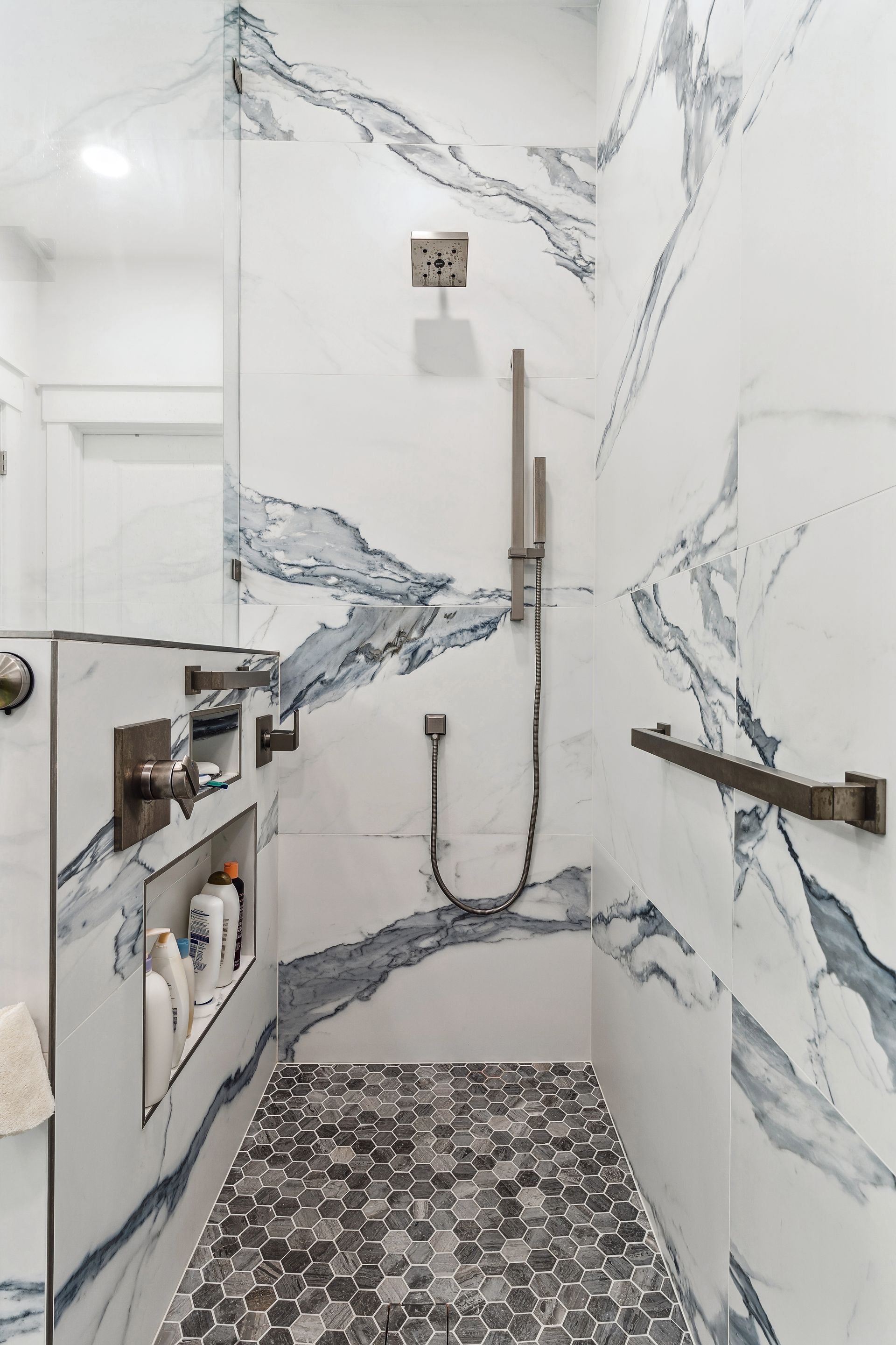 A bathroom with a walk in shower and a marble wall.