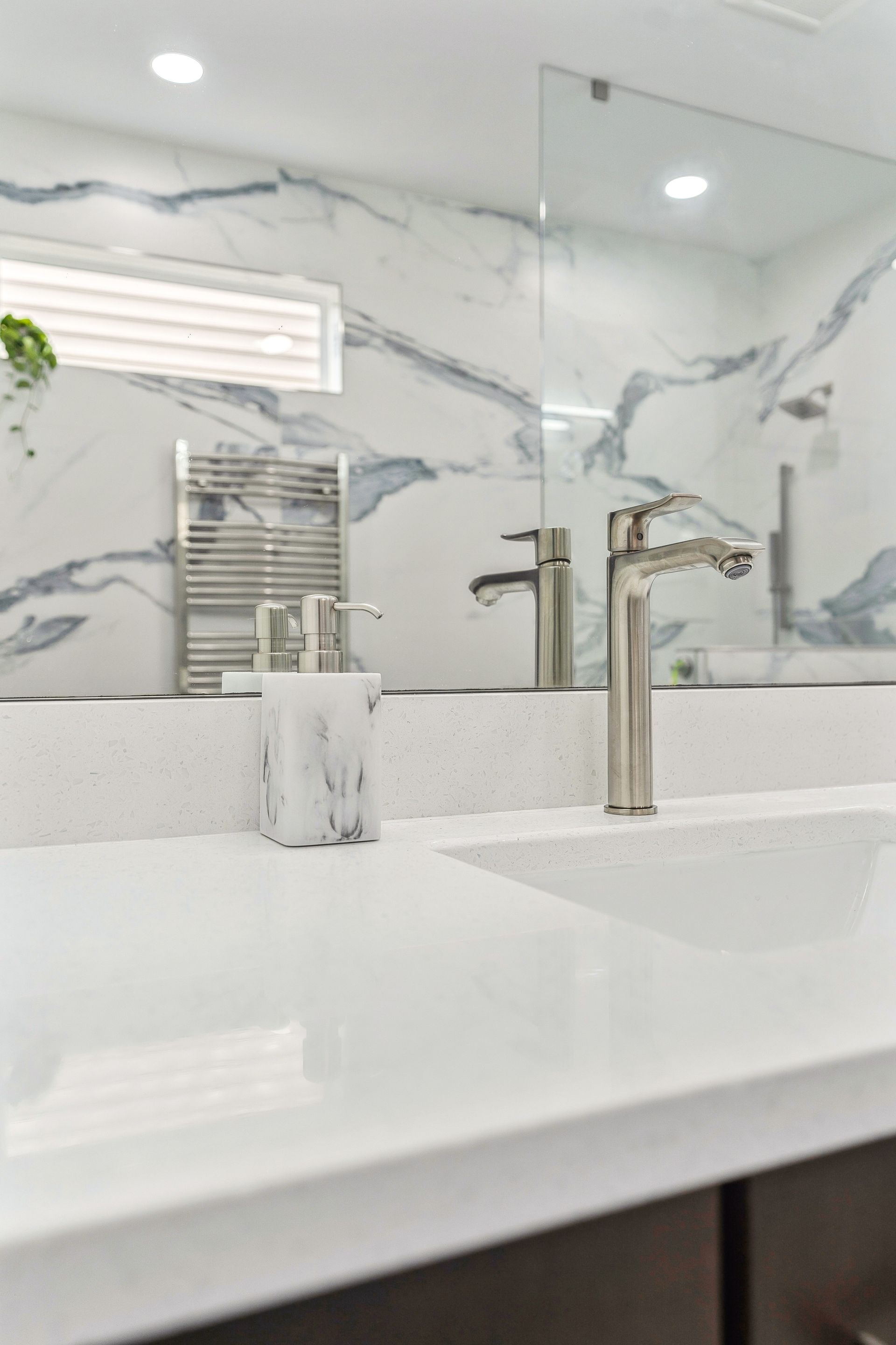 A bathroom with a sink, mirror and towel rack.
