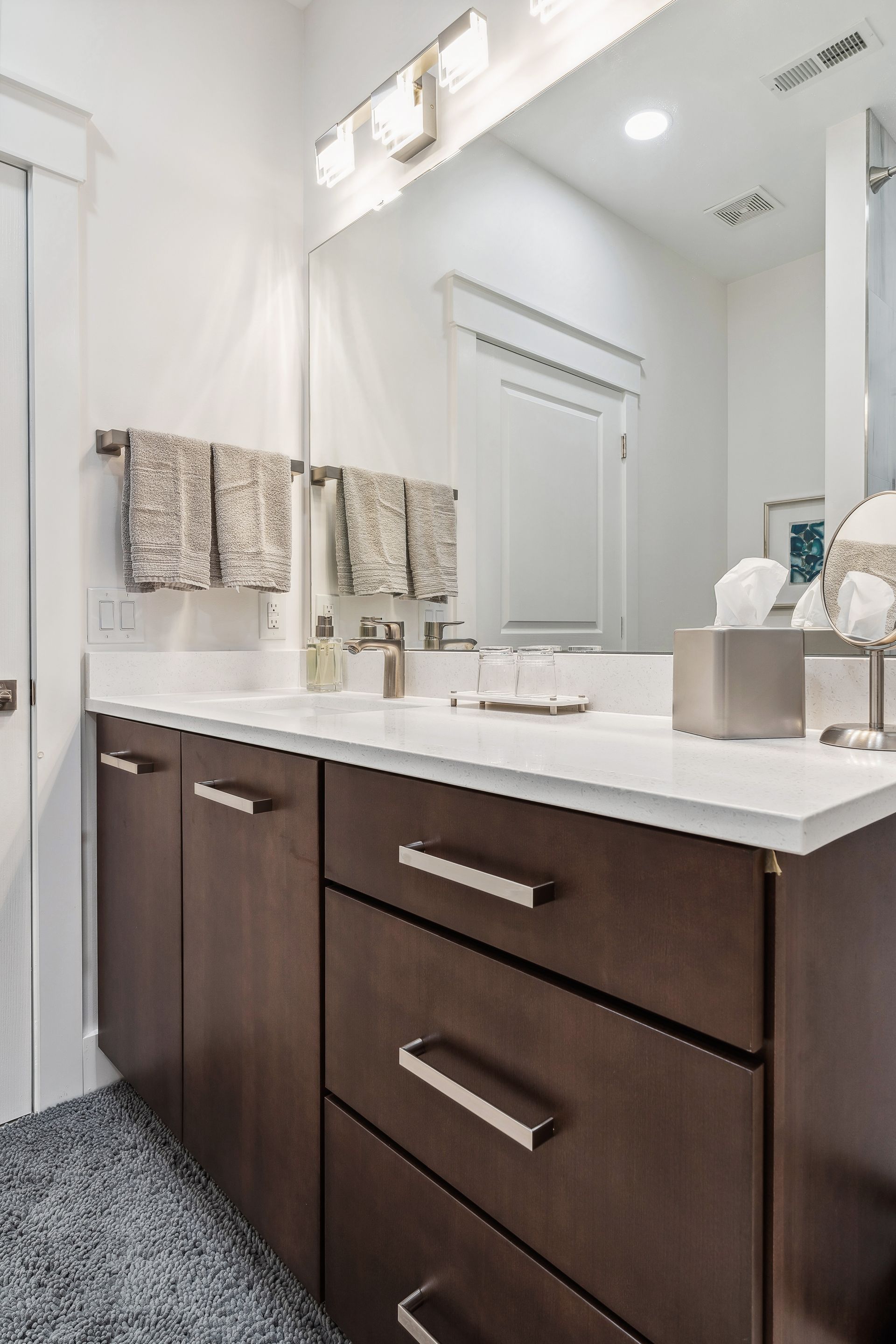 A bathroom with a sink, mirror, cabinets and drawers.