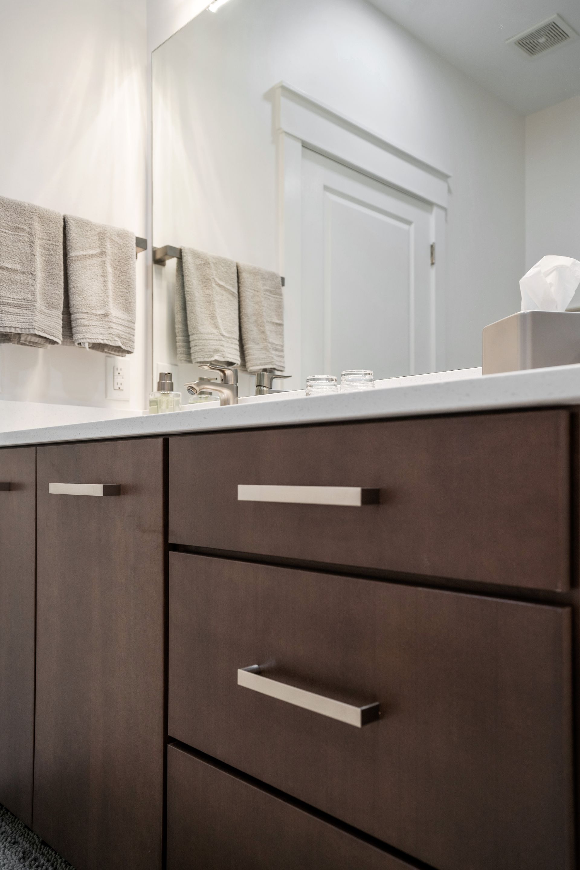 A bathroom with a sink, mirror and drawers.