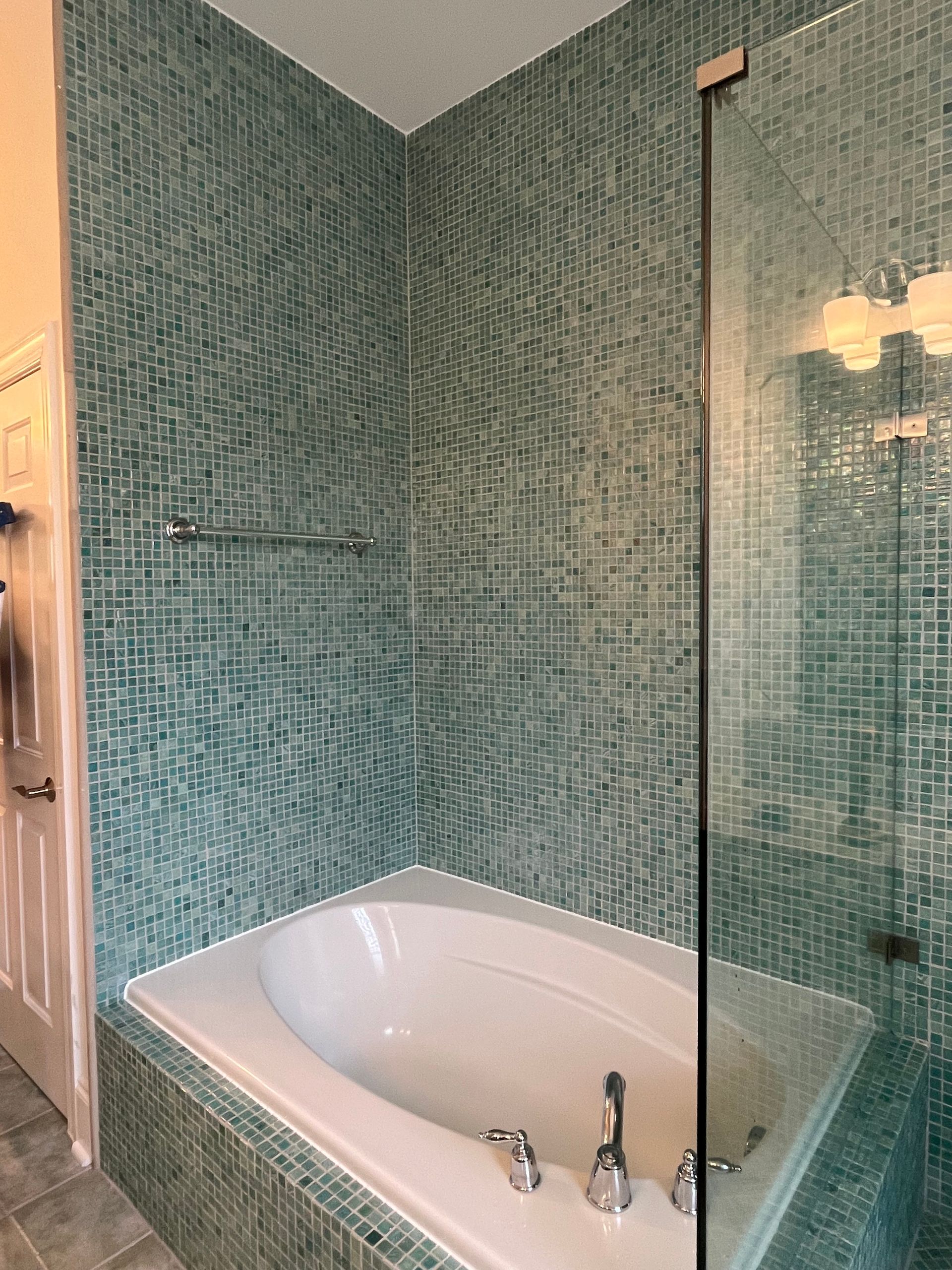 A bathtub in a bathroom next to a shower with a glass door.
