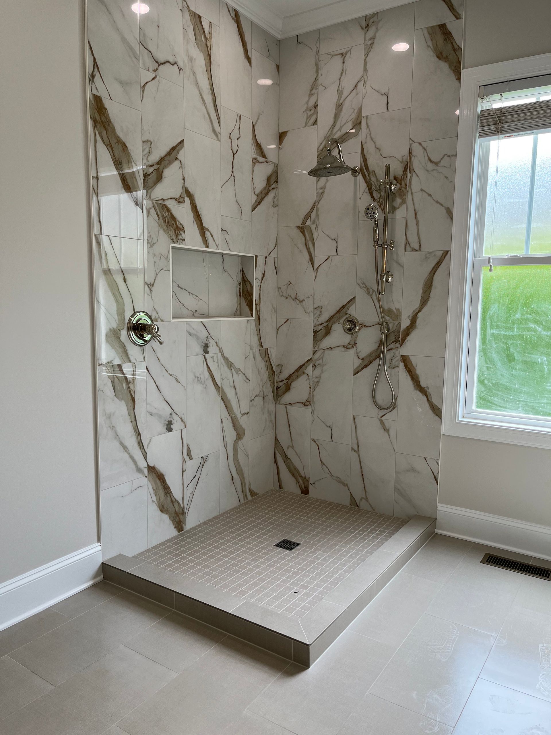A bathroom with a walk in shower and a window.