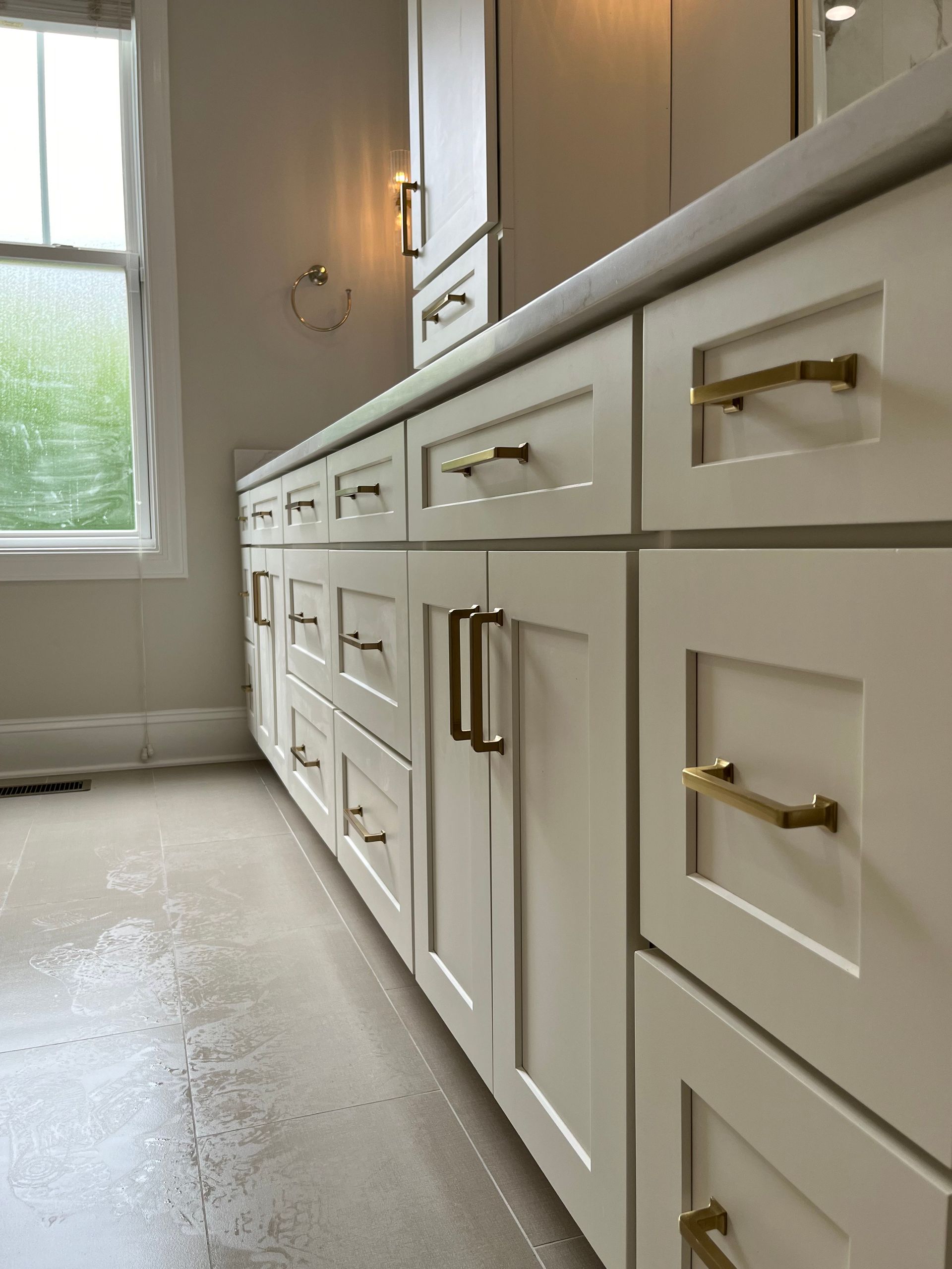 A bathroom with white cabinets and gold handles