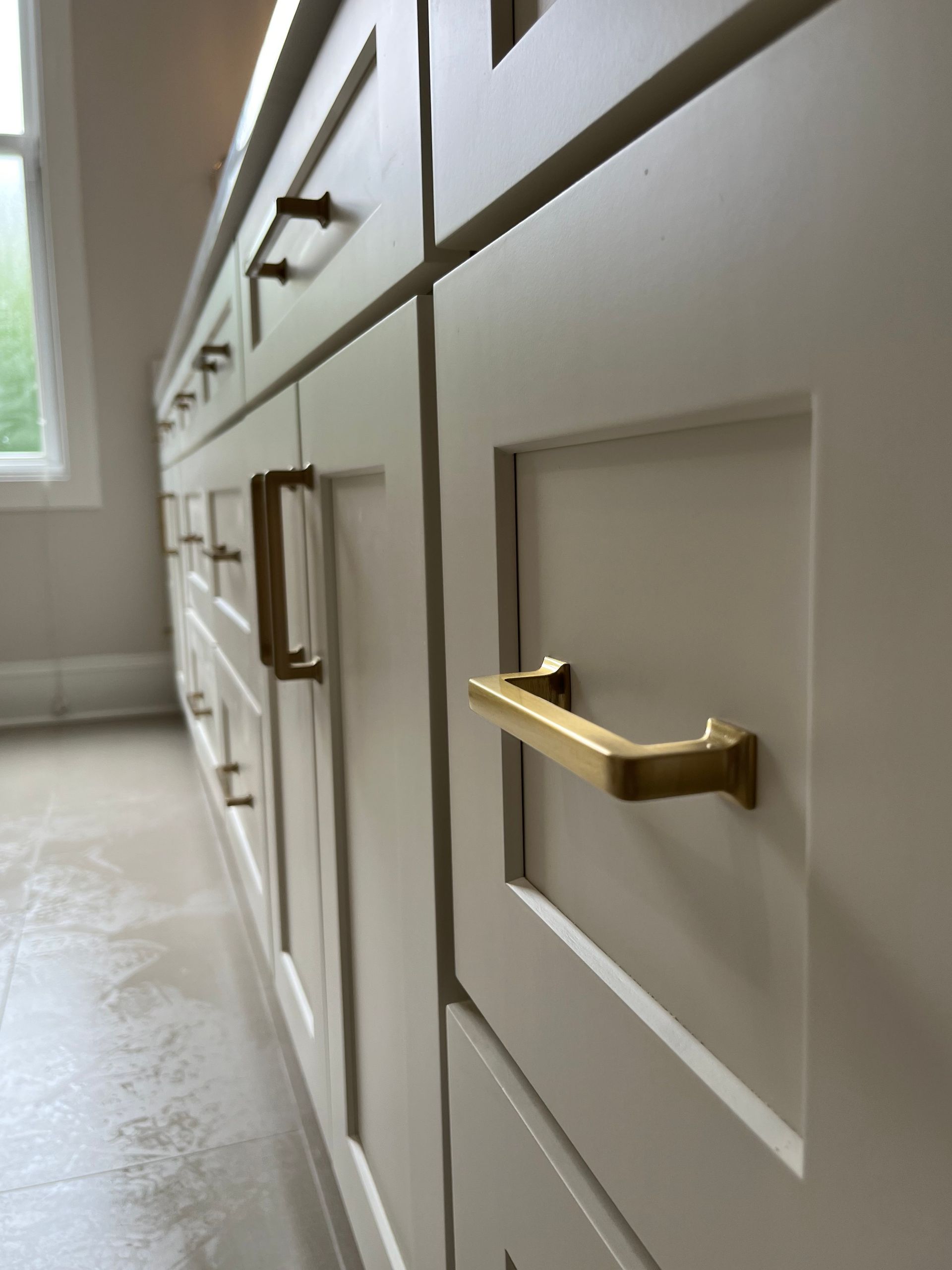 A kitchen with white cabinets and brass handles