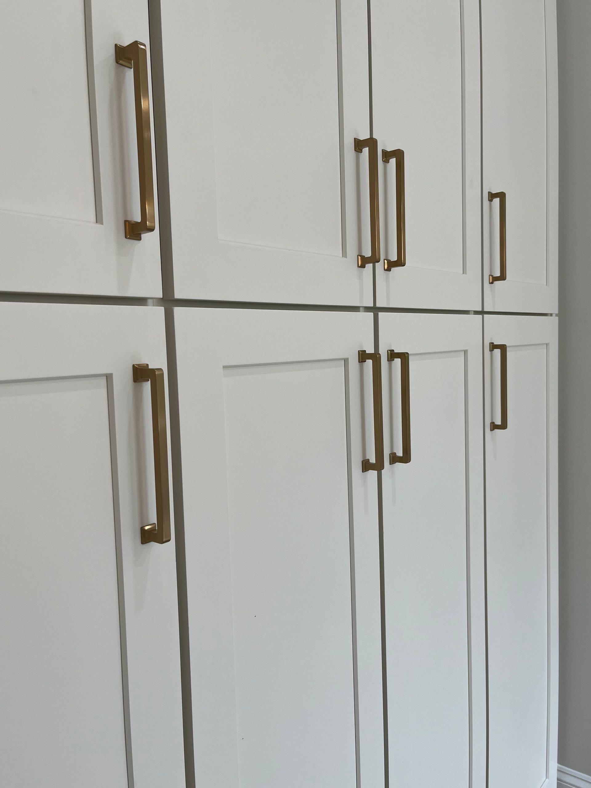 A row of white cabinets with gold handles