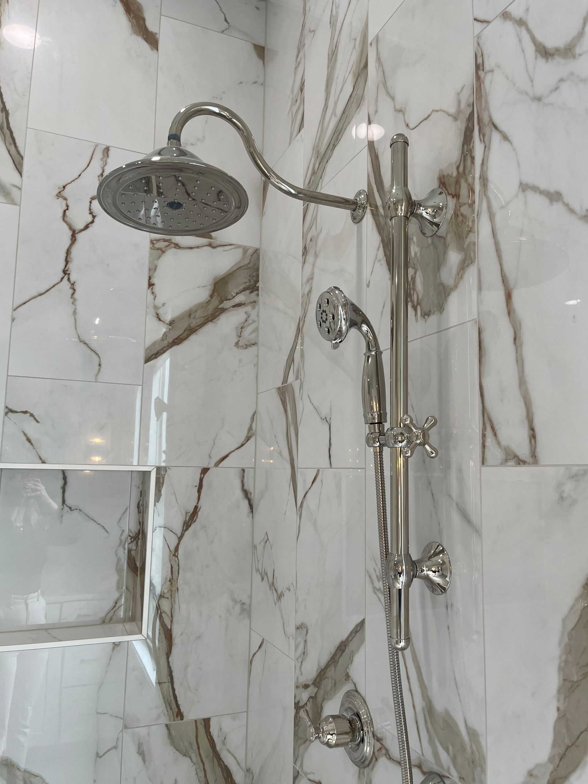 A bathroom with marble tiles and a shower head