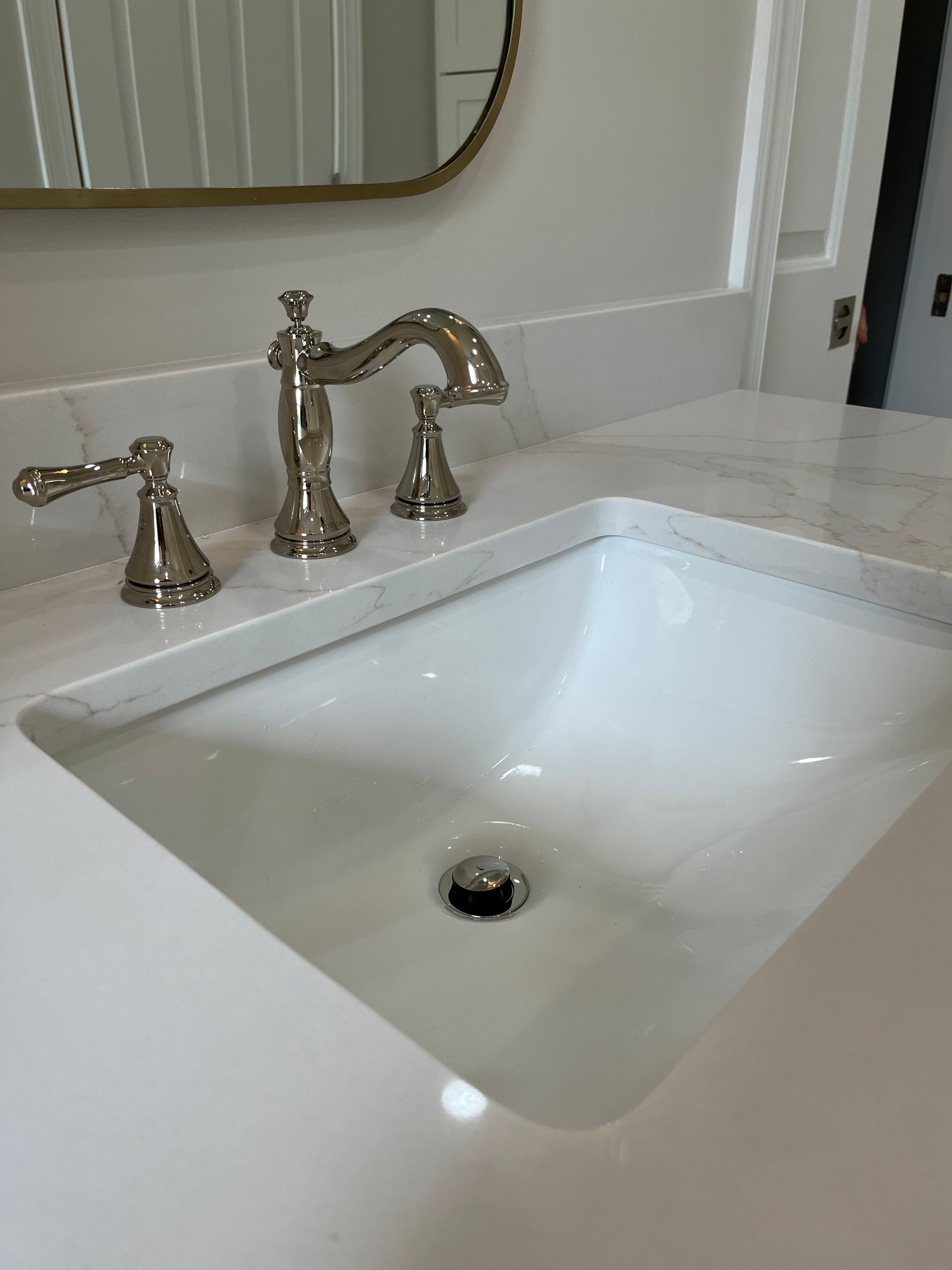 A bathroom sink with a faucet and a mirror.