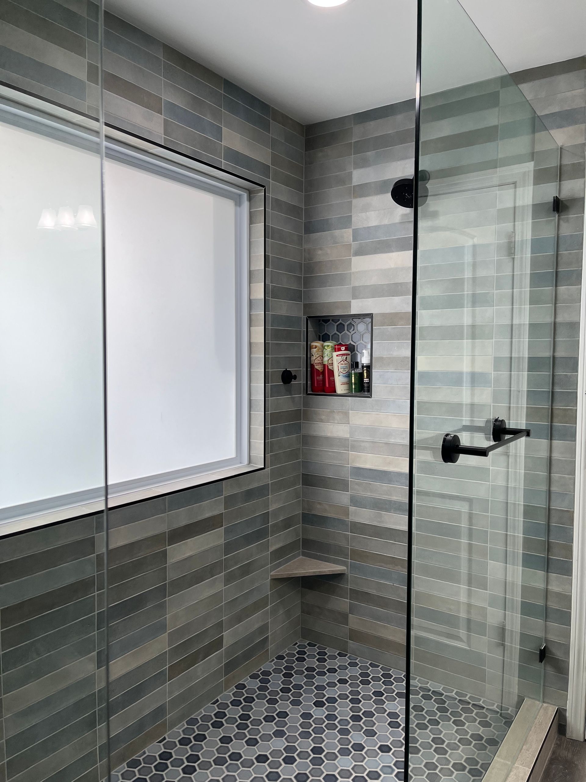 A bathroom with a walk in shower and a window.