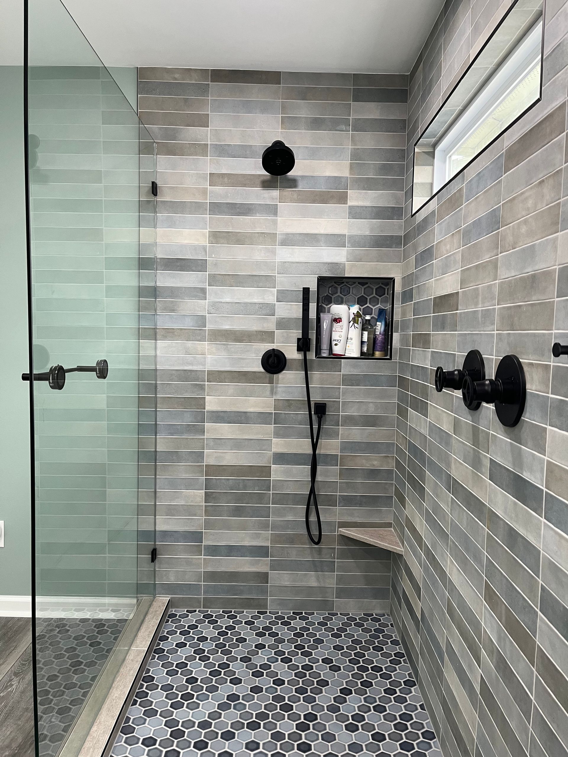 A bathroom with a walk in shower and a glass door.