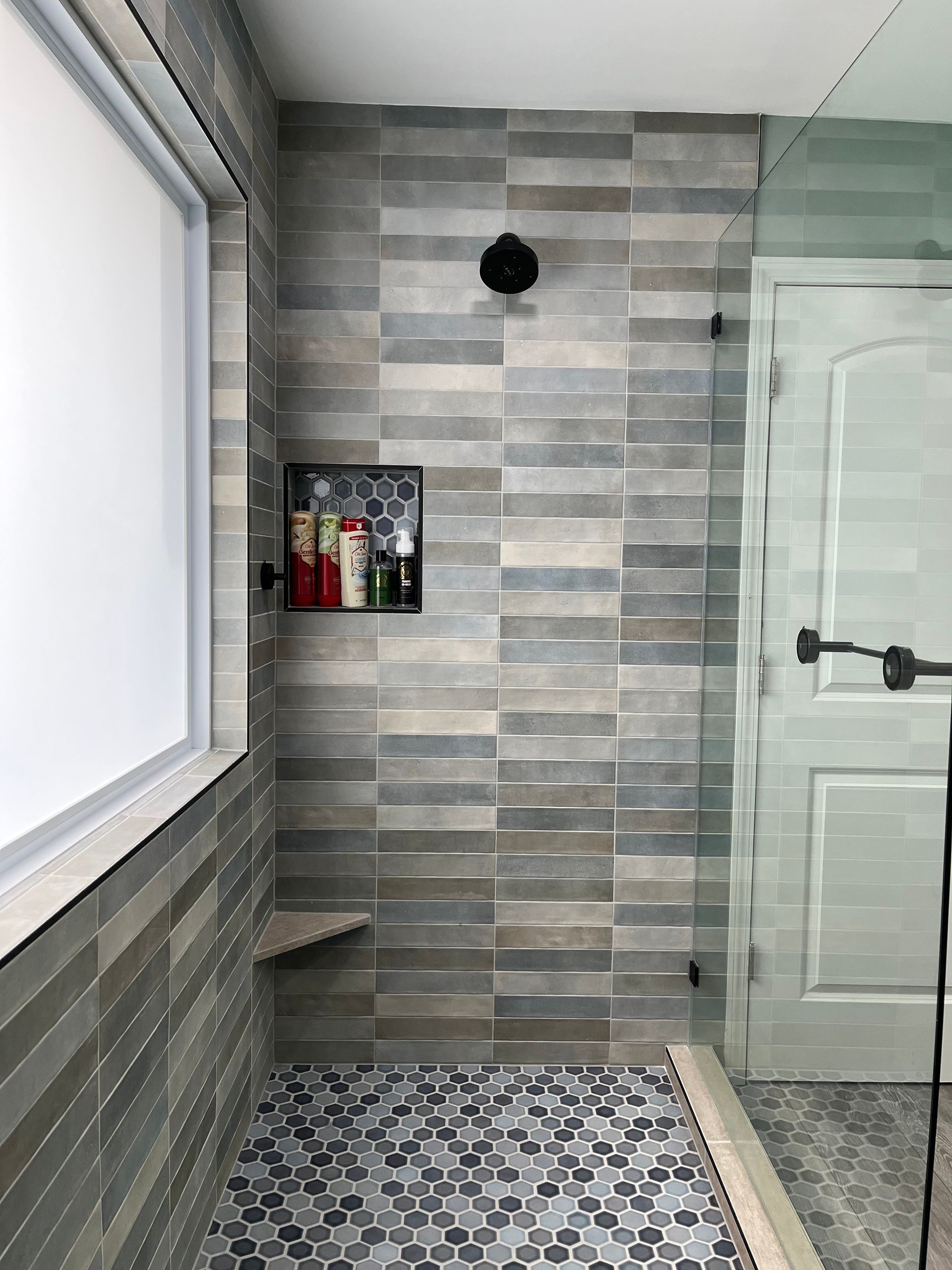 A bathroom with a walk in shower and a window.