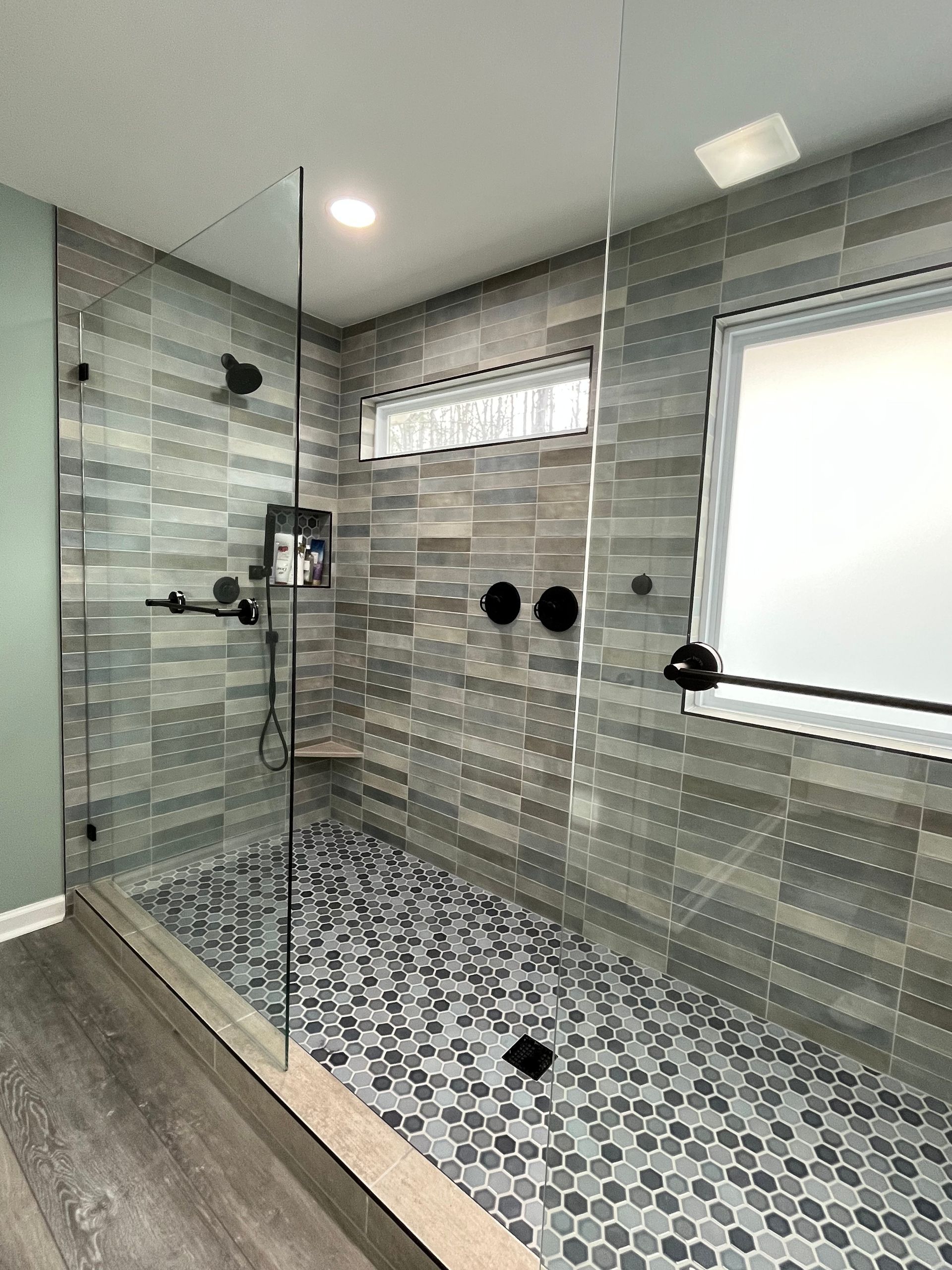 A bathroom with a walk in shower and a window.