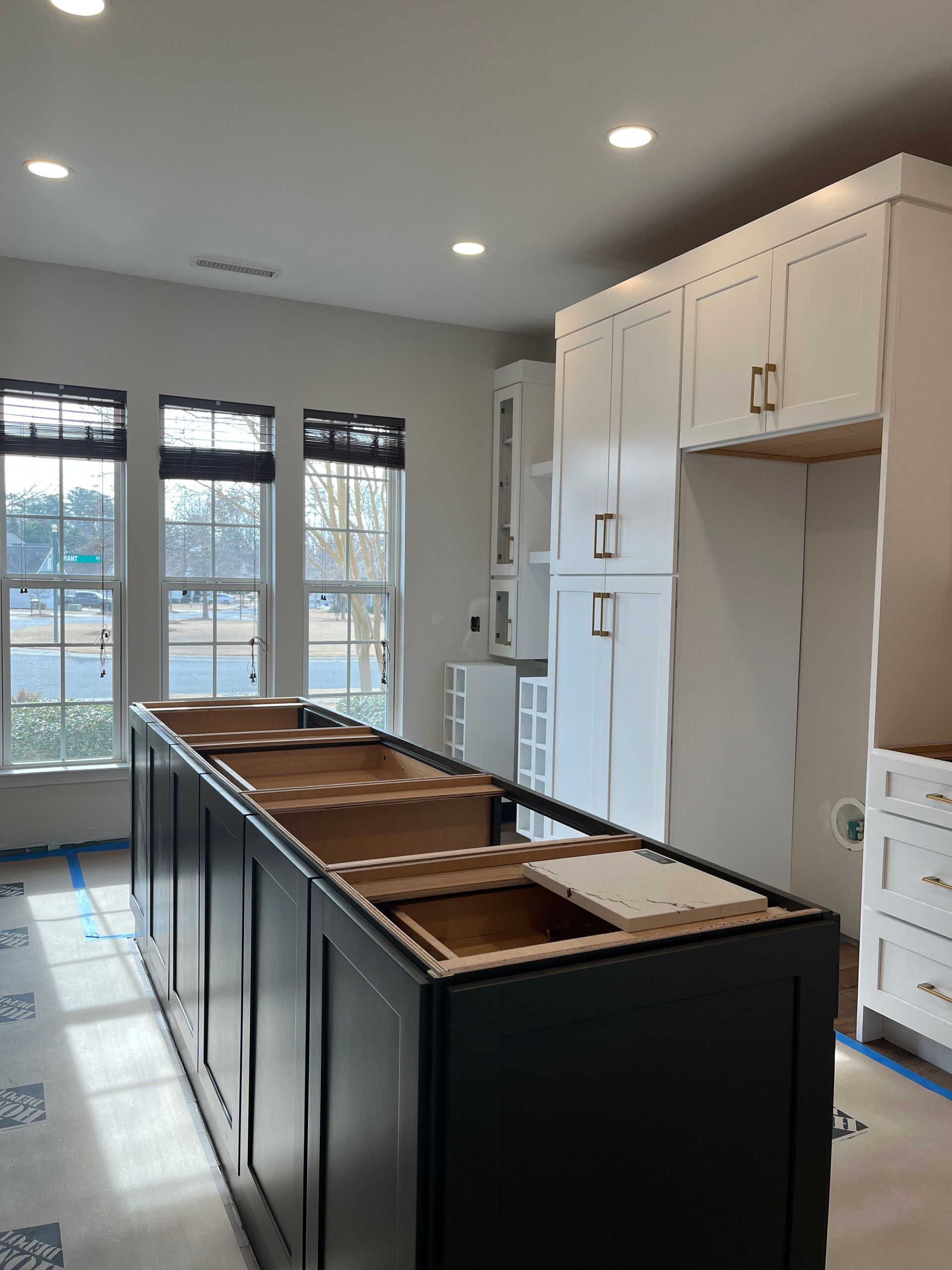 A kitchen with black cabinets and white cabinets under construction