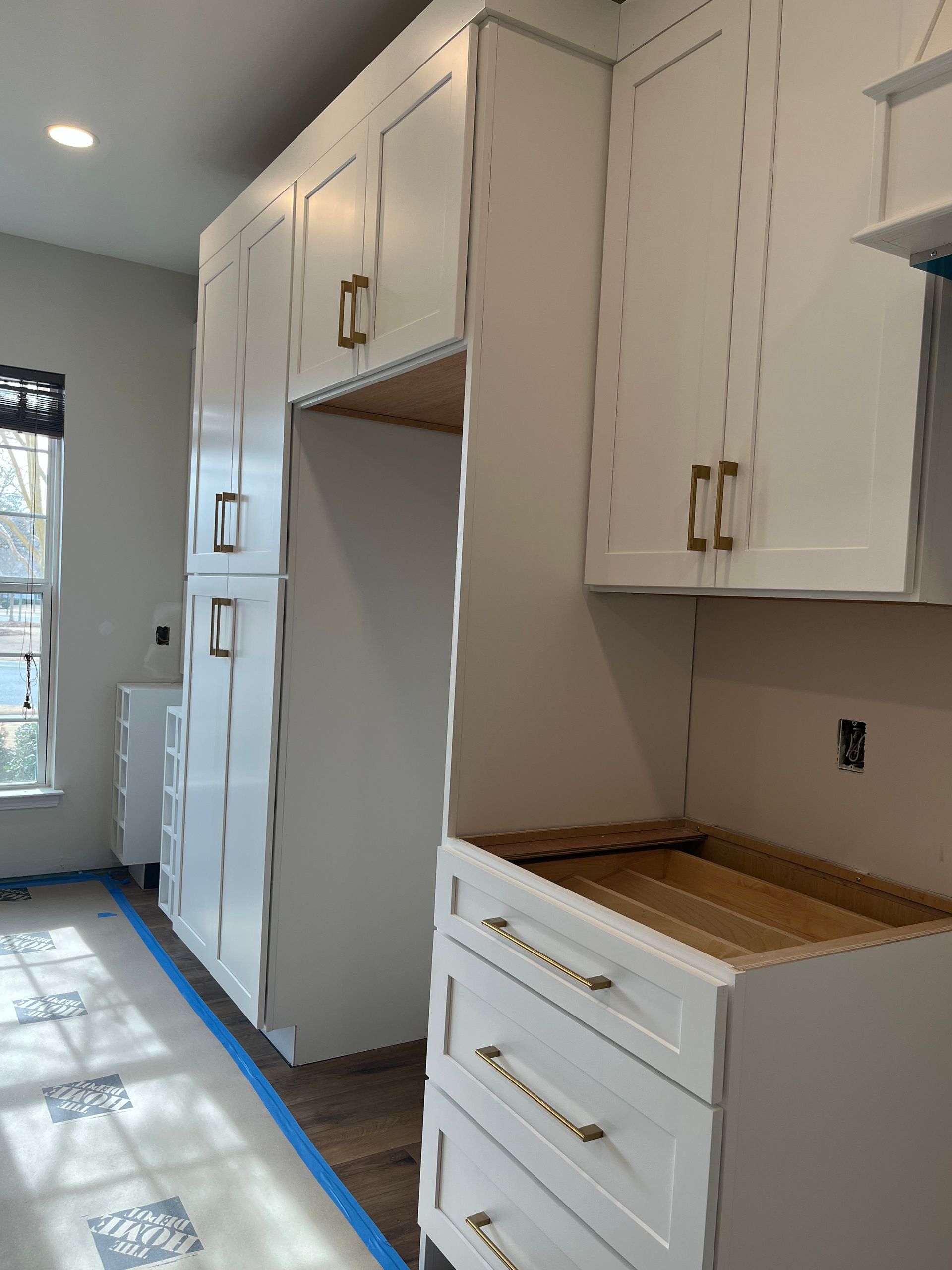 A kitchen with white cabinets and drawers and a window