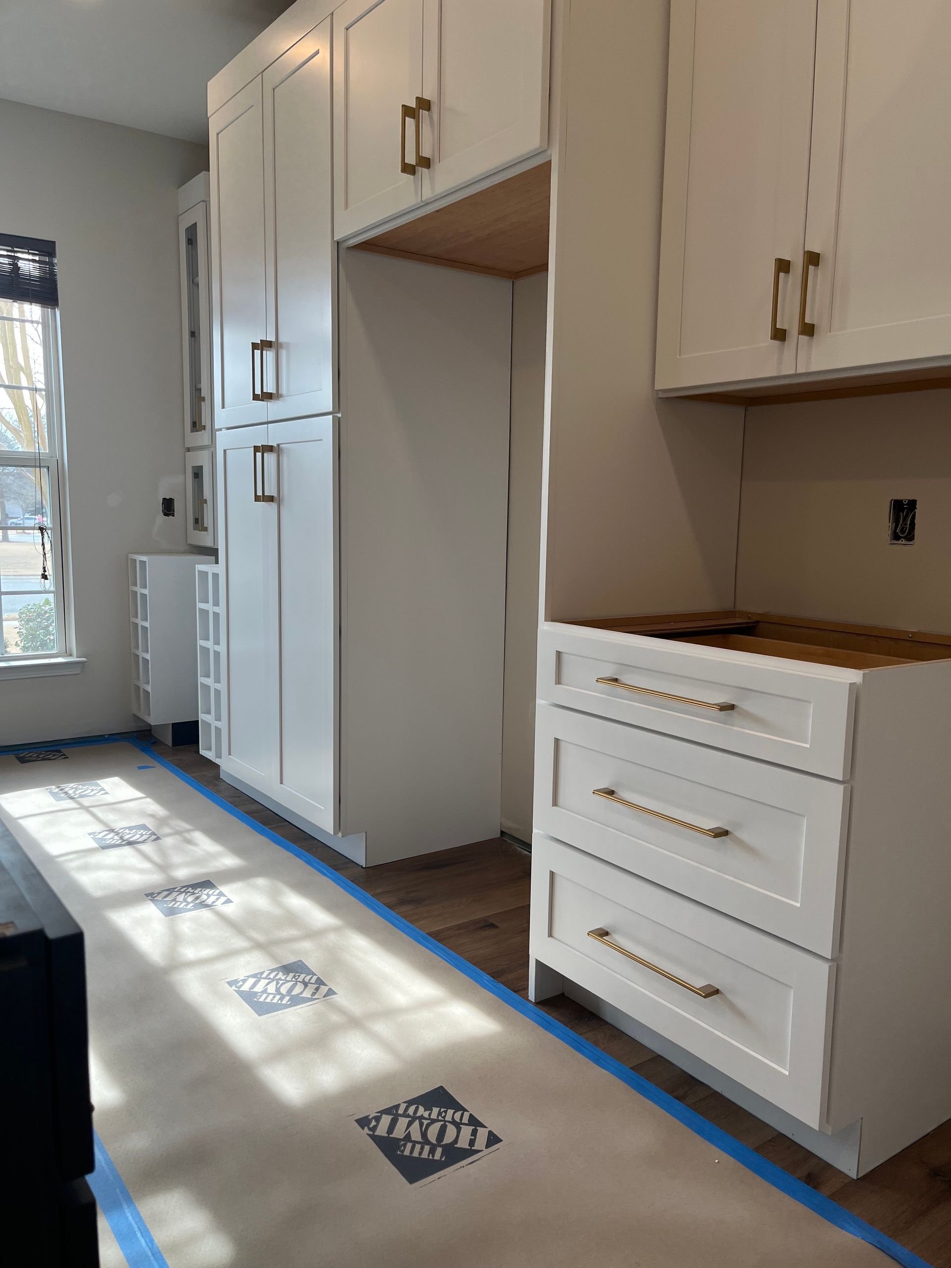 A kitchen with white cabinets and blue tape on the floor.