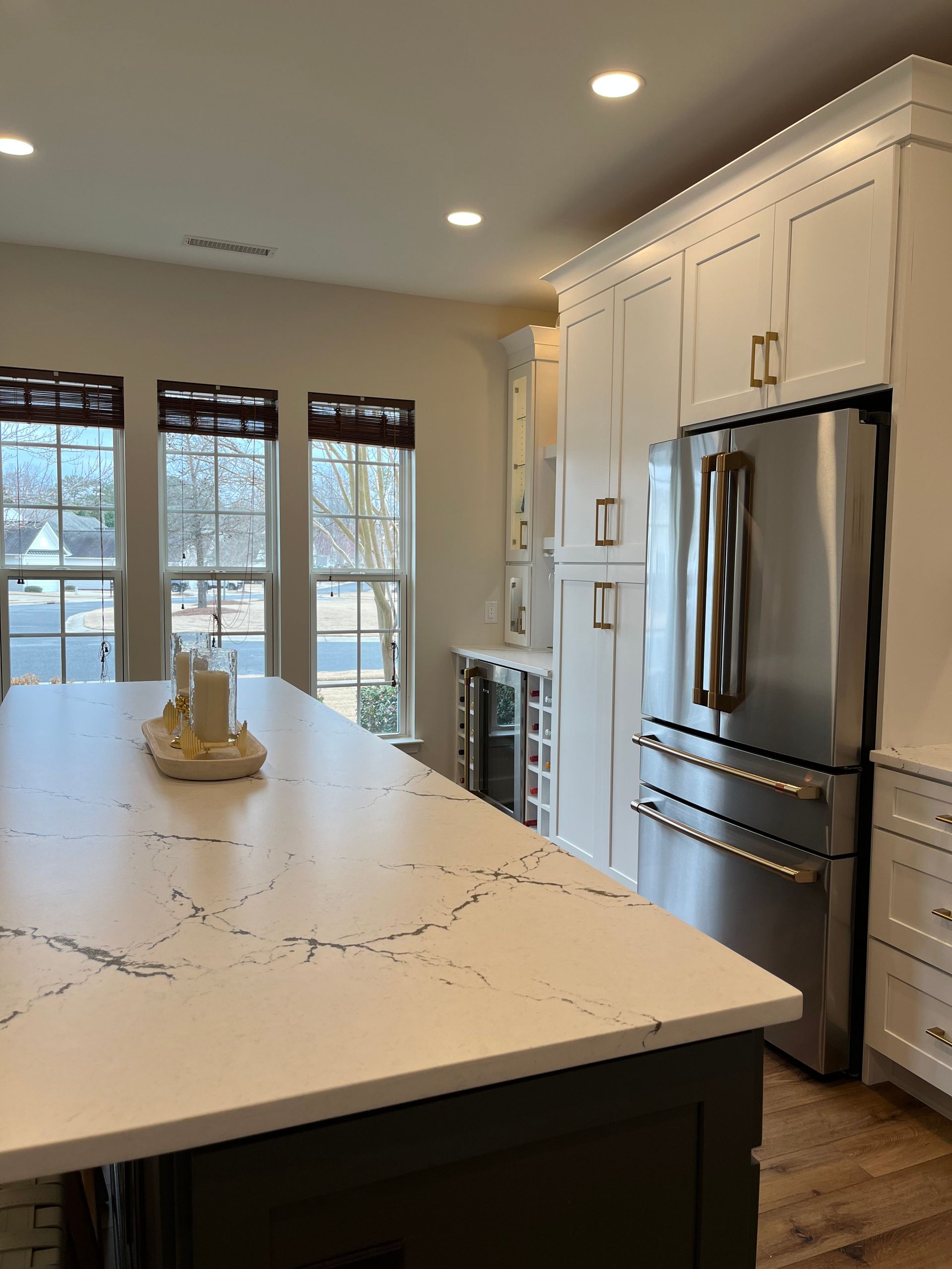 A kitchen with white cabinets, stainless steel appliances and a large island.