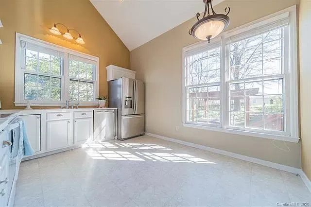 An empty kitchen with a refrigerator and a lot of windows.