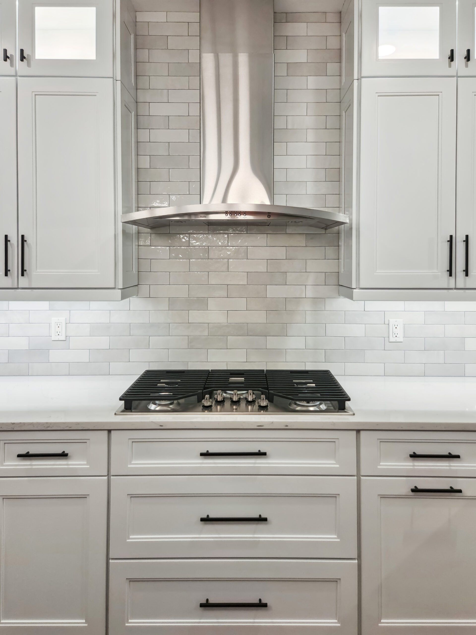 A kitchen with white cabinets and a stove top oven.