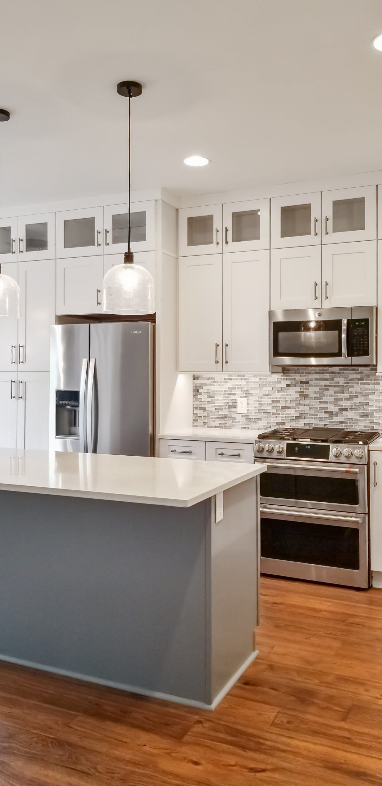 A kitchen with white cabinets , stainless steel appliances , and a large island.