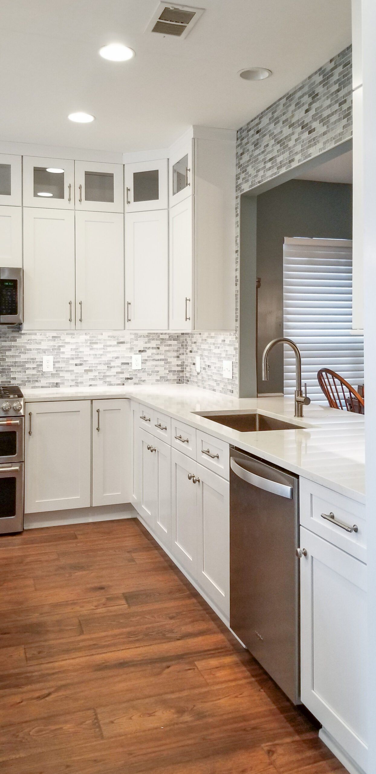 A kitchen with white cabinets , stainless steel appliances , and hardwood floors.