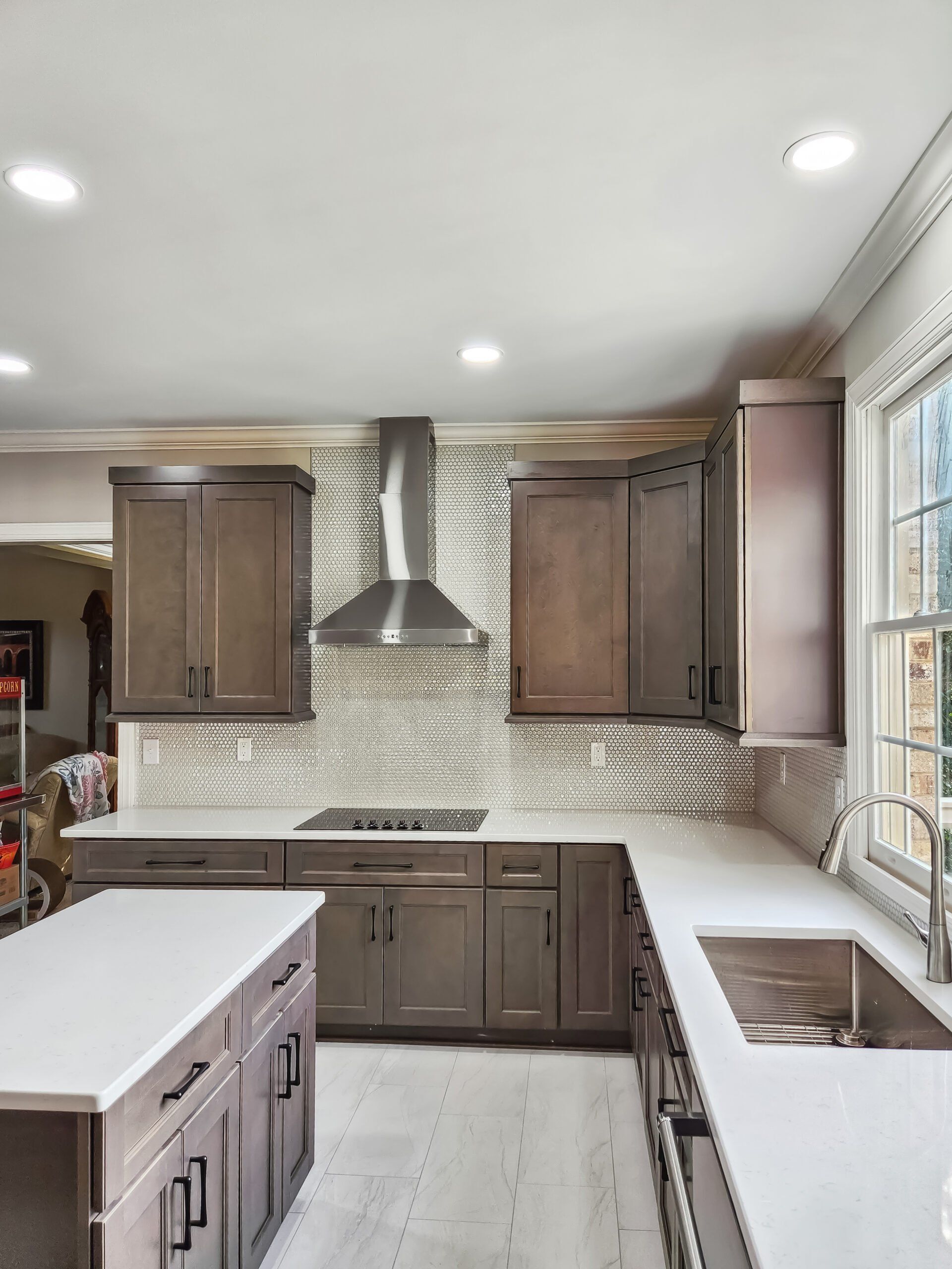 A kitchen with wooden cabinets , white counter tops , stainless steel appliances and a large island.